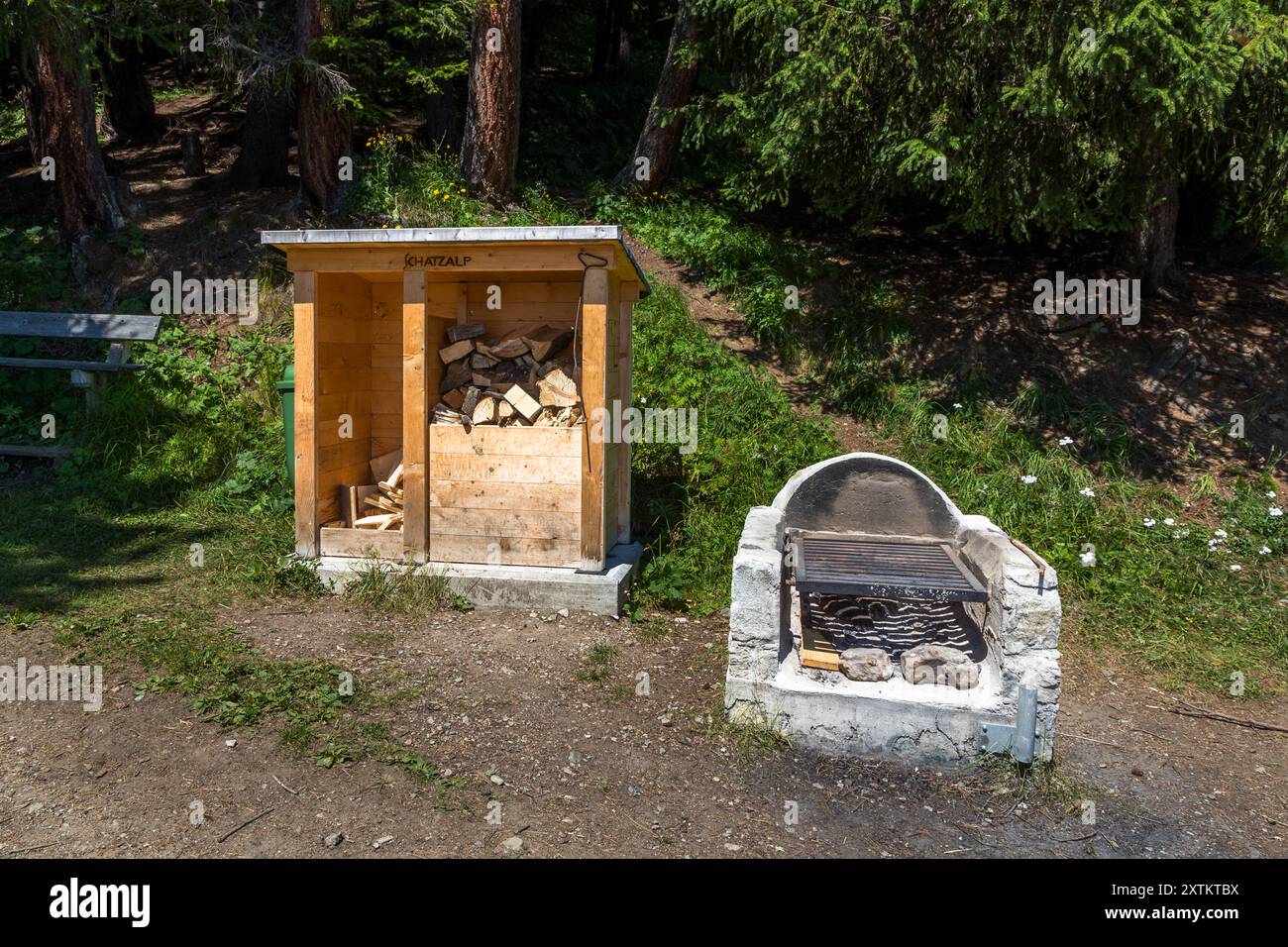 Un abri en bois étiqueté 'Schatzalp' et une cheminée en pierre se dressent côte à côte le long du Wasserfallweg au-dessus de la Schatzalp, Davos, Grisons, Suisse. L'abri est rempli de bois de chauffage pour la cheminée. Banque D'Images