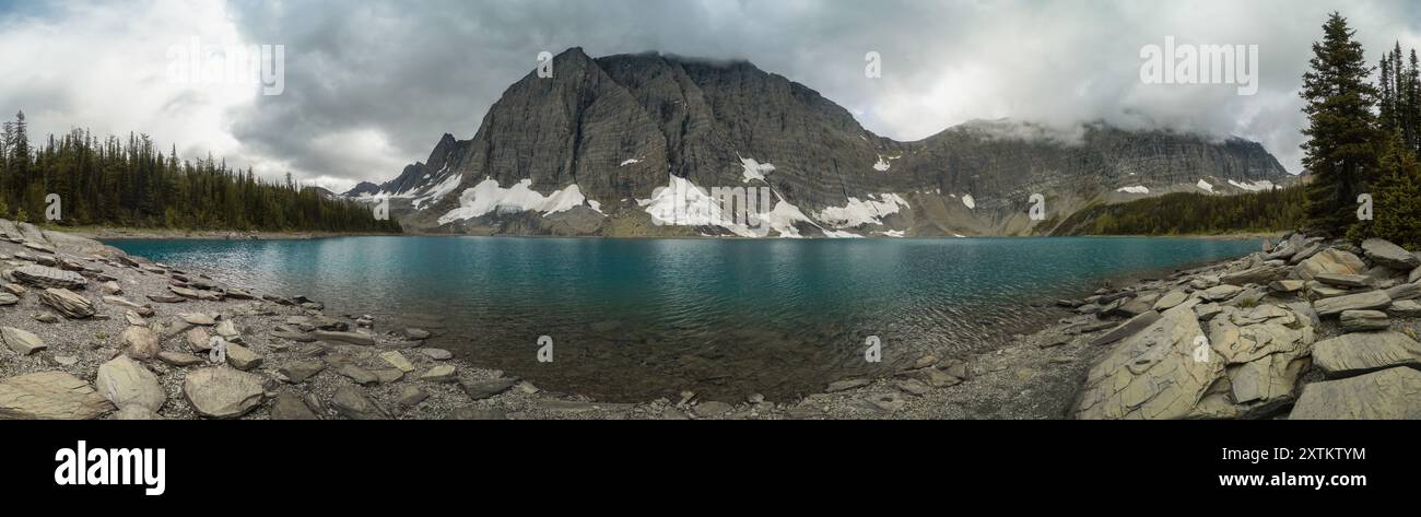 Une chaîne de montagnes avec un grand plan d'eau au premier plan. Le ciel est nuageux et l'eau est bleue Banque D'Images