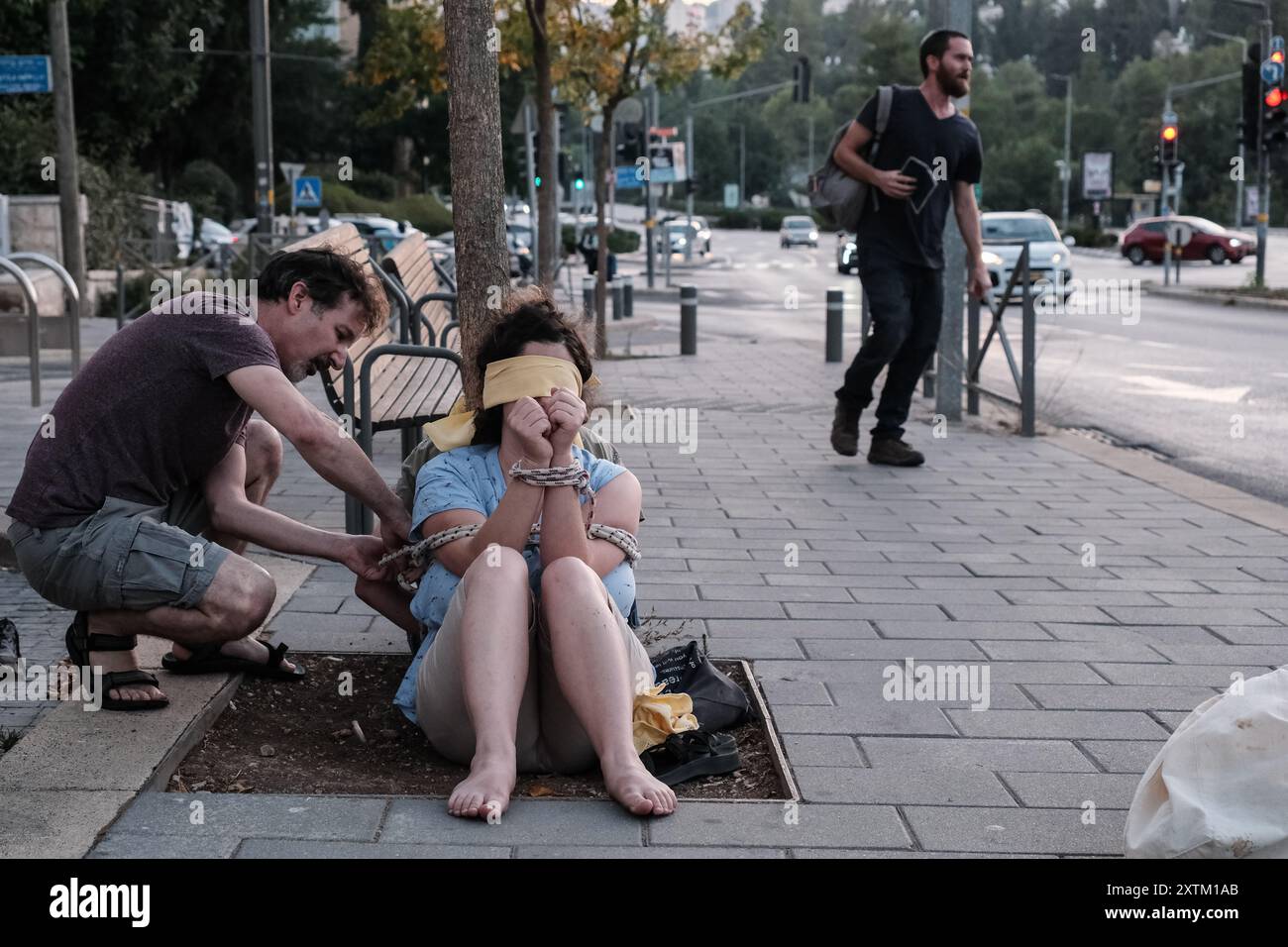 Jérusalem, Israël. 15 août 2024. Les activistes manifestent leur solidarité avec les otages israéliens à Gaza en se ligotant et en se bandant les yeux dans des lieux publics, des manifestations similaires apparaissant spontanément dans tout le pays. Les manifestants exigent un accord de libération immédiate des otages. Le conflit en cours entre Israël et le Hamas, déclenché par des tirs massifs de roquettes depuis Gaza et l’infiltration d’hommes armés palestiniens le 7 octobre 2023, a entraîné le massacre de 1 400 civils et l’enlèvement d’environ 240 personnes, dont des bébés, des enfants et des soldats. Avec 115 otages encore en captivité, beaucoup sont HOL Banque D'Images