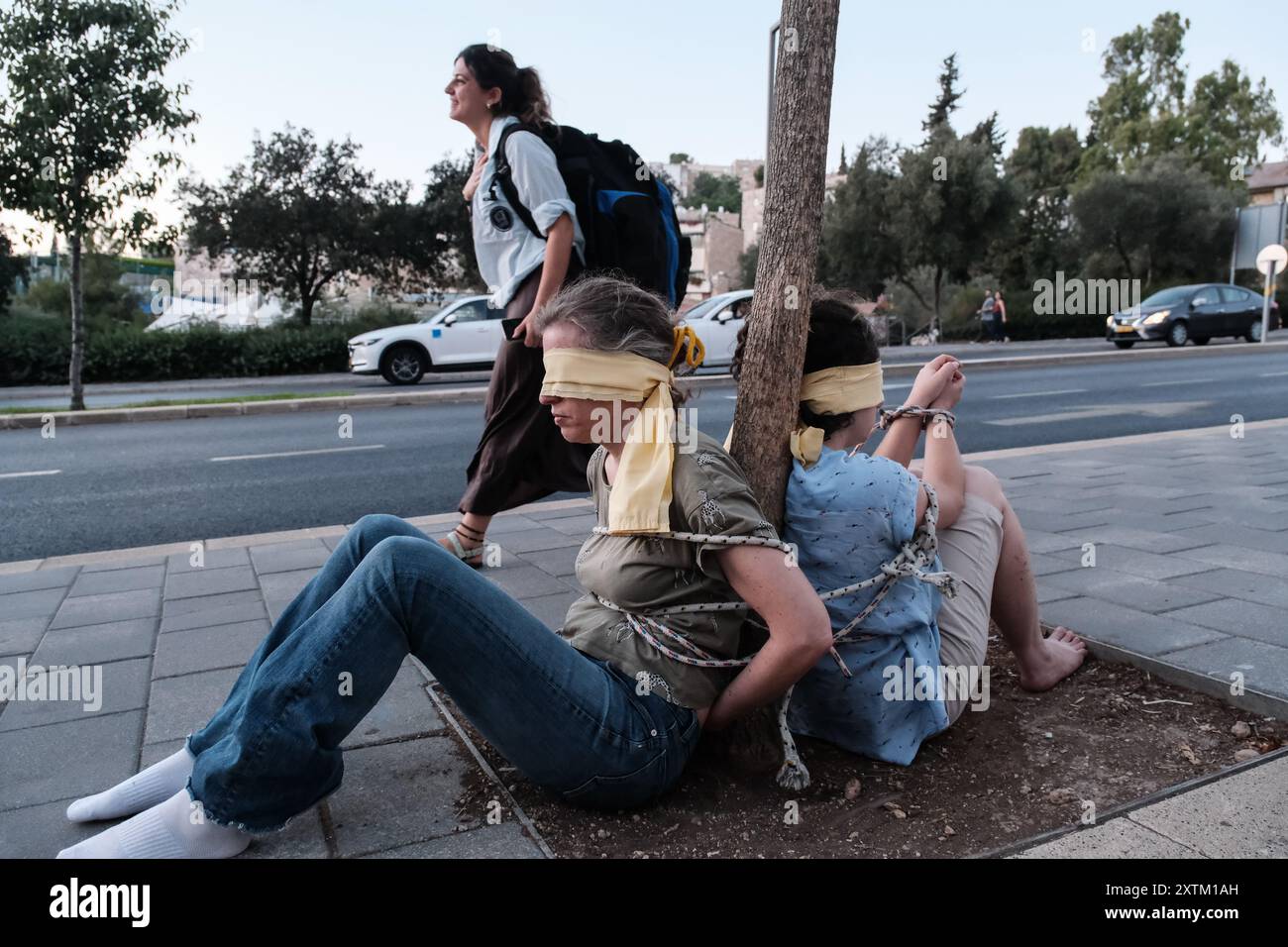 Jérusalem, Israël. 15 août 2024. Les activistes manifestent leur solidarité avec les otages israéliens à Gaza en se ligotant et en se bandant les yeux dans des lieux publics, des manifestations similaires apparaissant spontanément dans tout le pays. Les manifestants exigent un accord de libération immédiate des otages. Le conflit en cours entre Israël et le Hamas, déclenché par des tirs massifs de roquettes depuis Gaza et l’infiltration d’hommes armés palestiniens le 7 octobre 2023, a entraîné le massacre de 1 400 civils et l’enlèvement d’environ 240 personnes, dont des bébés, des enfants et des soldats. Avec 115 otages encore en captivité, beaucoup sont HOL Banque D'Images