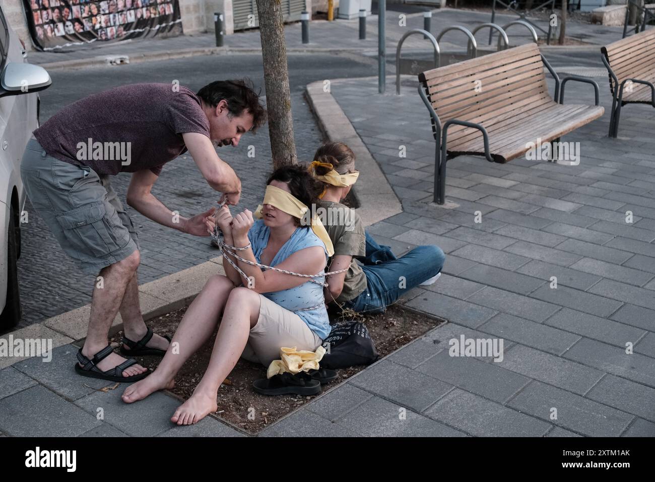 Jérusalem, Israël. 15 août 2024. Les activistes manifestent leur solidarité avec les otages israéliens à Gaza en se ligotant et en se bandant les yeux dans des lieux publics, des manifestations similaires apparaissant spontanément dans tout le pays. Les manifestants exigent un accord de libération immédiate des otages. Le conflit en cours entre Israël et le Hamas, déclenché par des tirs massifs de roquettes depuis Gaza et l’infiltration d’hommes armés palestiniens le 7 octobre 2023, a entraîné le massacre de 1 400 civils et l’enlèvement d’environ 240 personnes, dont des bébés, des enfants et des soldats. Avec 115 otages encore en captivité, beaucoup sont HOL Banque D'Images