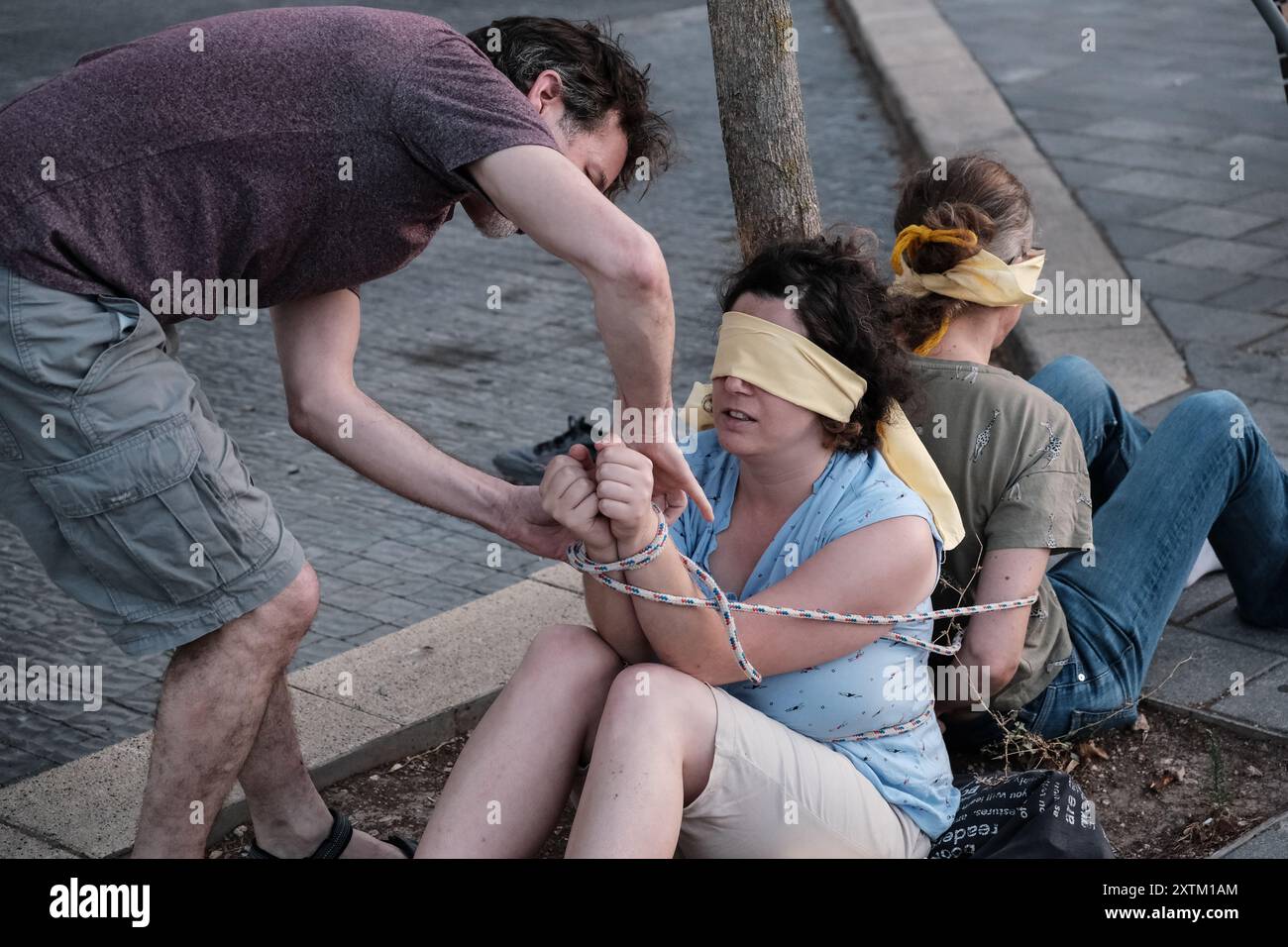 Jérusalem, Israël. 15 août 2024. Les activistes manifestent leur solidarité avec les otages israéliens à Gaza en se ligotant et en se bandant les yeux dans des lieux publics, des manifestations similaires apparaissant spontanément dans tout le pays. Les manifestants exigent un accord de libération immédiate des otages. Le conflit en cours entre Israël et le Hamas, déclenché par des tirs massifs de roquettes depuis Gaza et l’infiltration d’hommes armés palestiniens le 7 octobre 2023, a entraîné le massacre de 1 400 civils et l’enlèvement d’environ 240 personnes, dont des bébés, des enfants et des soldats. Avec 115 otages encore en captivité, beaucoup sont HOL Banque D'Images