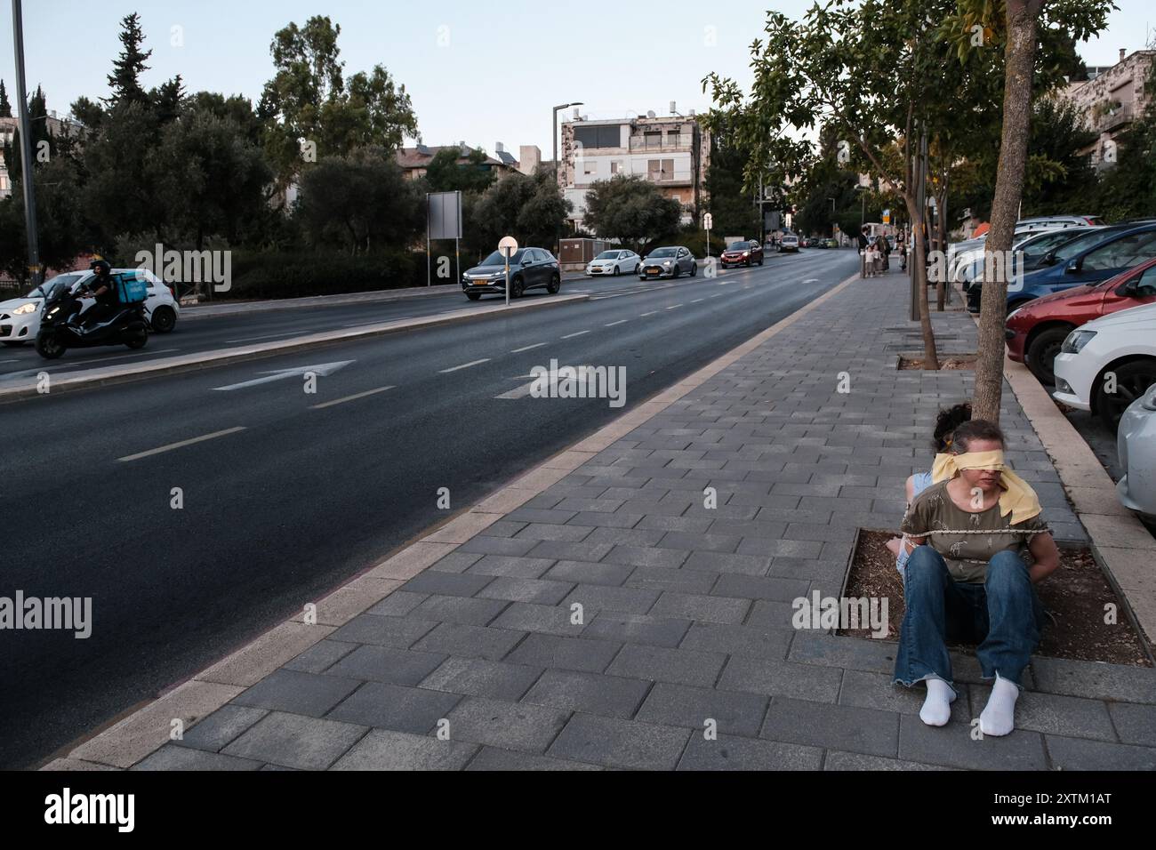 Jérusalem, Israël. 15 août 2024. Les activistes manifestent leur solidarité avec les otages israéliens à Gaza en se ligotant et en se bandant les yeux dans des lieux publics, des manifestations similaires apparaissant spontanément dans tout le pays. Les manifestants exigent un accord de libération immédiate des otages. Le conflit en cours entre Israël et le Hamas, déclenché par des tirs massifs de roquettes depuis Gaza et l’infiltration d’hommes armés palestiniens le 7 octobre 2023, a entraîné le massacre de 1 400 civils et l’enlèvement d’environ 240 personnes, dont des bébés, des enfants et des soldats. Avec 115 otages encore en captivité, beaucoup sont HOL Banque D'Images