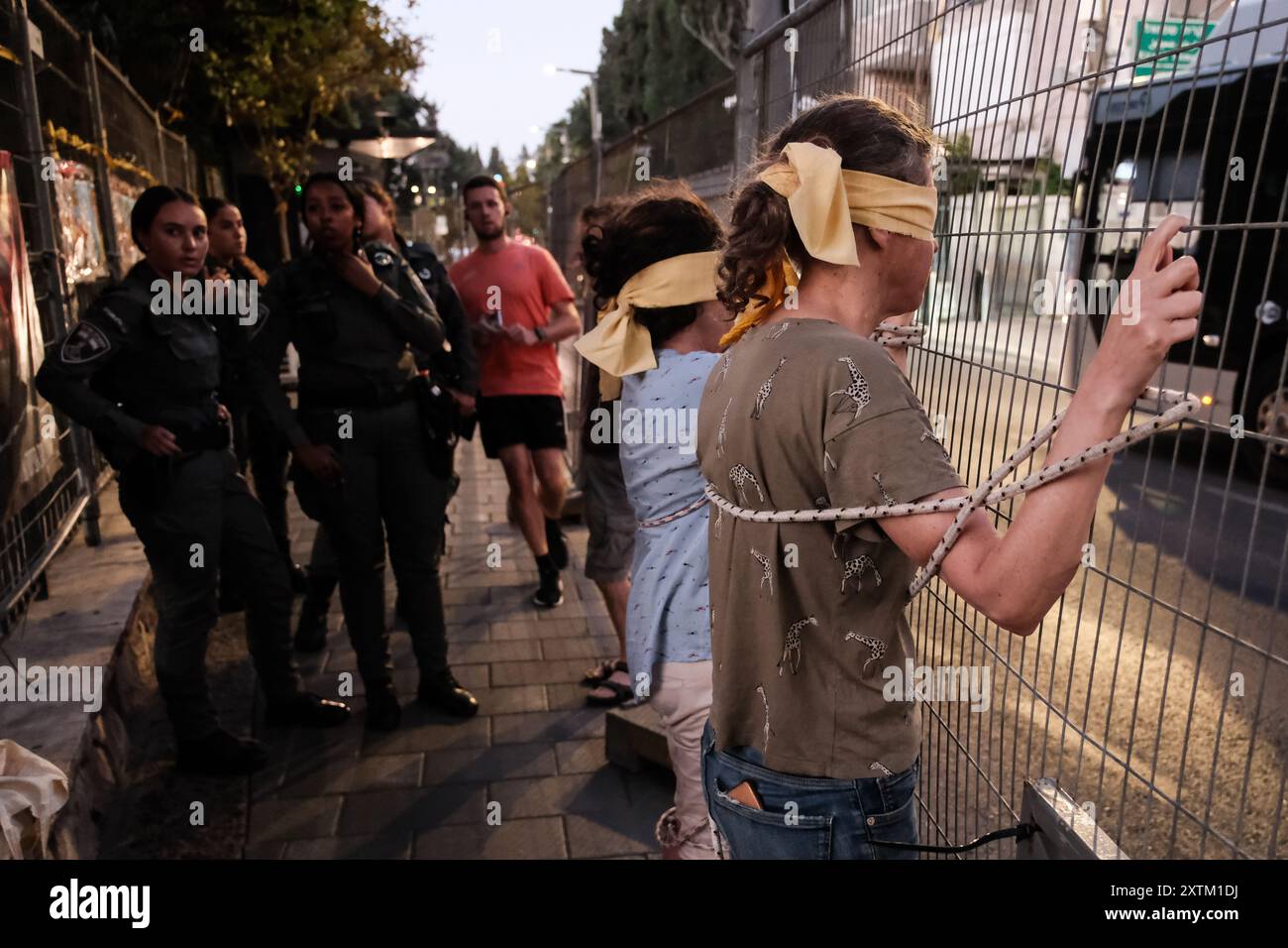 Jérusalem, Israël. 15 août 2024. Les activistes manifestent leur solidarité avec les otages israéliens à Gaza en se ligotant et en se bandant les yeux dans des lieux publics, des manifestations similaires apparaissant spontanément dans tout le pays. Les manifestants exigent un accord de libération immédiate des otages. Le conflit en cours entre Israël et le Hamas, déclenché par des tirs massifs de roquettes depuis Gaza et l’infiltration d’hommes armés palestiniens le 7 octobre 2023, a entraîné le massacre de 1 400 civils et l’enlèvement d’environ 240 personnes, dont des bébés, des enfants et des soldats. Avec 115 otages encore en captivité, beaucoup sont HOL Banque D'Images