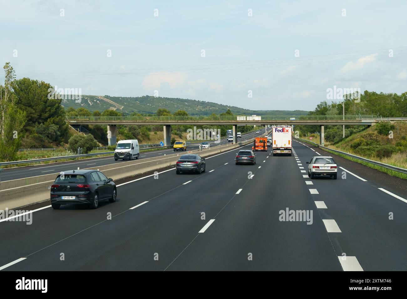 Nice, France - 6 juin 2023 : des voitures et un camion circulent sur une autoroute française lisse, passant sous un pont routier par une claire journée d'été. Banque D'Images