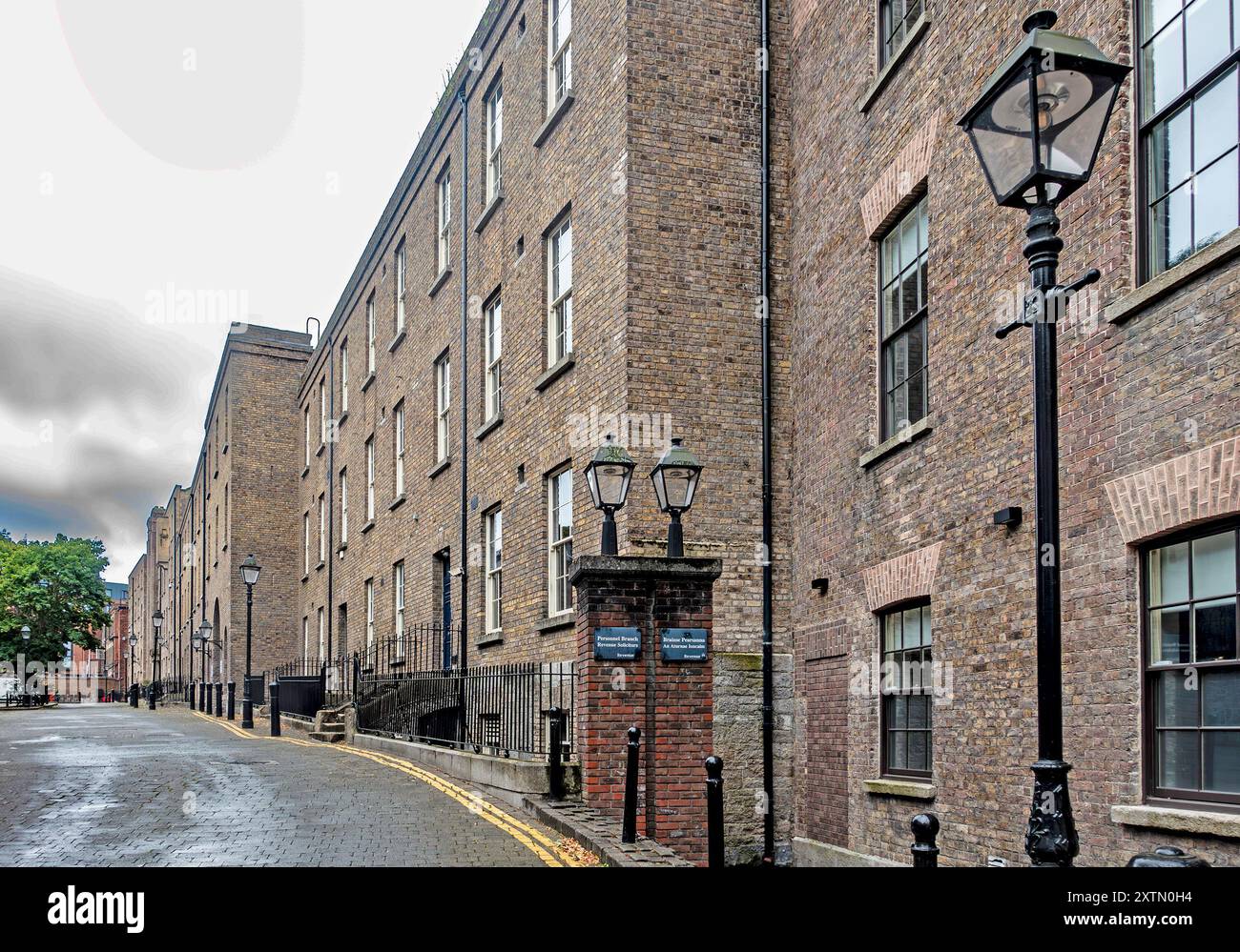 Vieux bâtiments historiques en briques dans le château de Dublin, Dublin, Irlande, se dressent le long d'une rue calme, avec des lampadaires illuminant le chemin. Banque D'Images