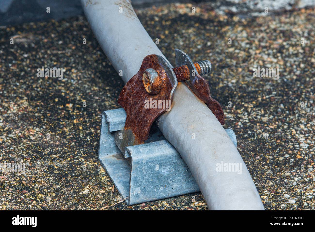 Collier en métal rouillé maintenant le conduit électrique sur le toit. Banque D'Images