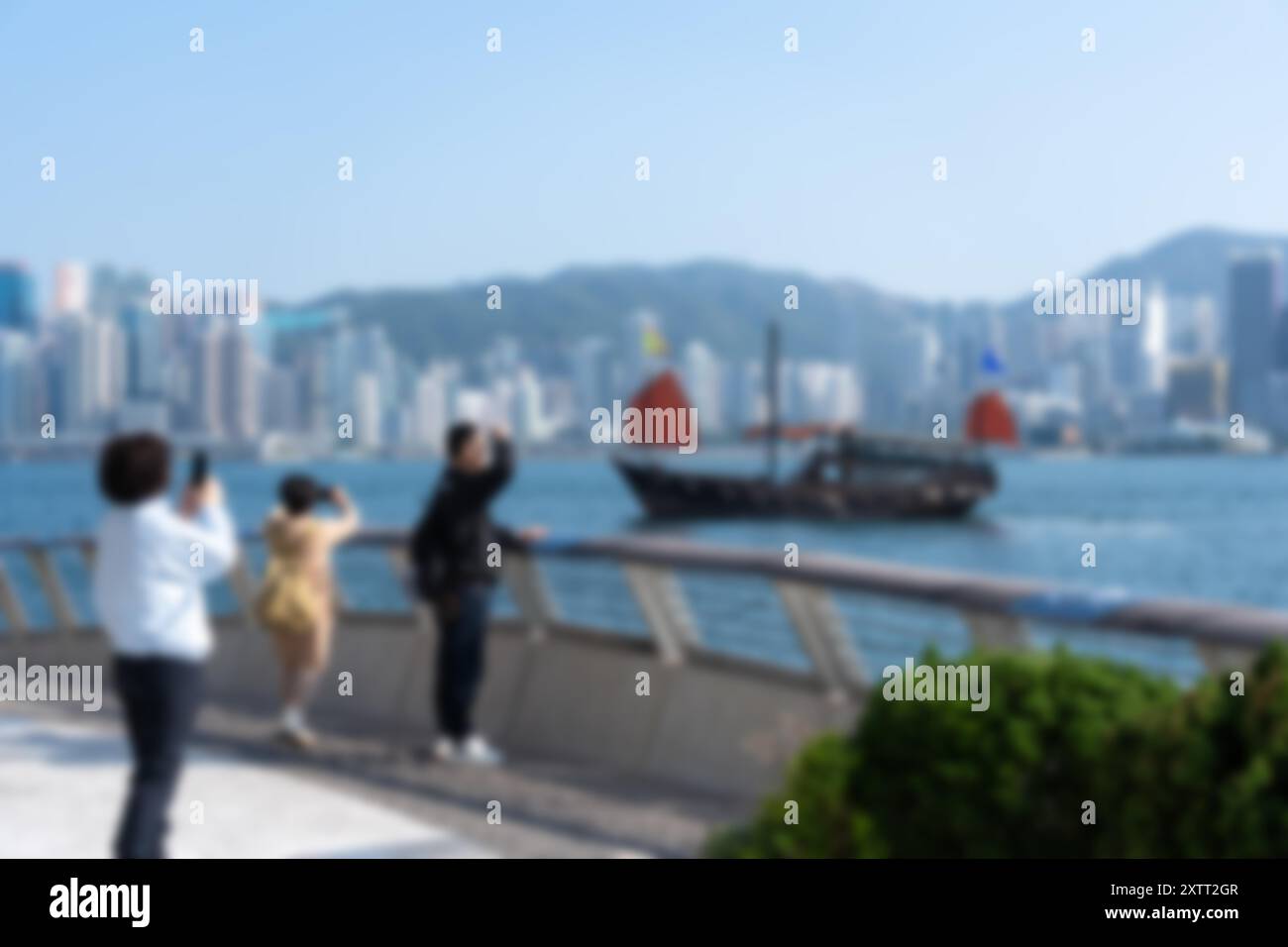 Vue floue sur le port Victoria à Hong Kong, en Chine, avec des touristes capturant des photos d'une jonque chinoise traditionnelle. Banque D'Images