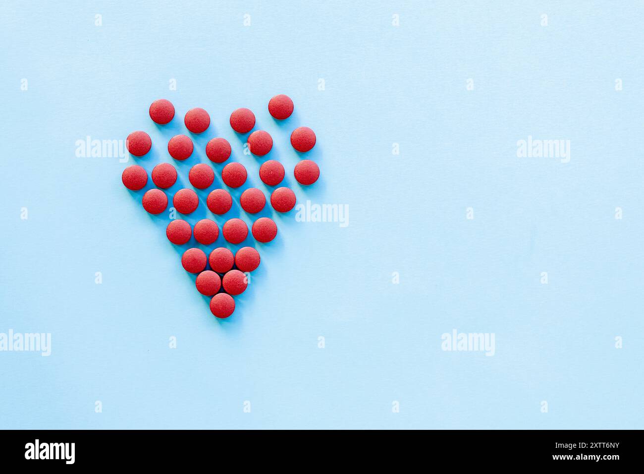pilules rouges vives en forme de cœur sur un fond bleu clair.abstract sur le thème d'un cœur sain, les maladies cardiaques Banque D'Images