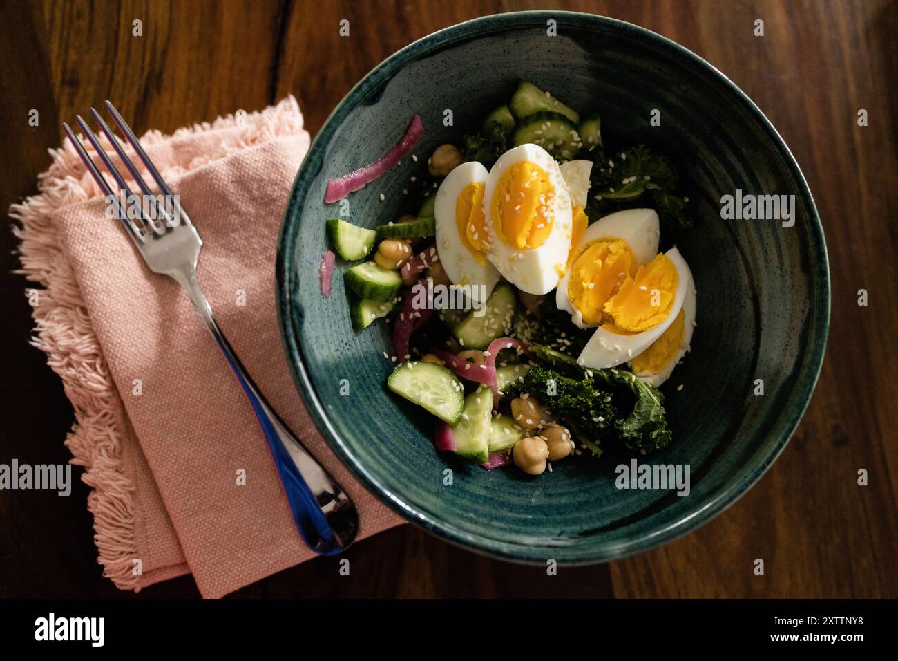 Salade verte garnie d'oeuf dur dans un bol vert sur la table de ferme Banque D'Images