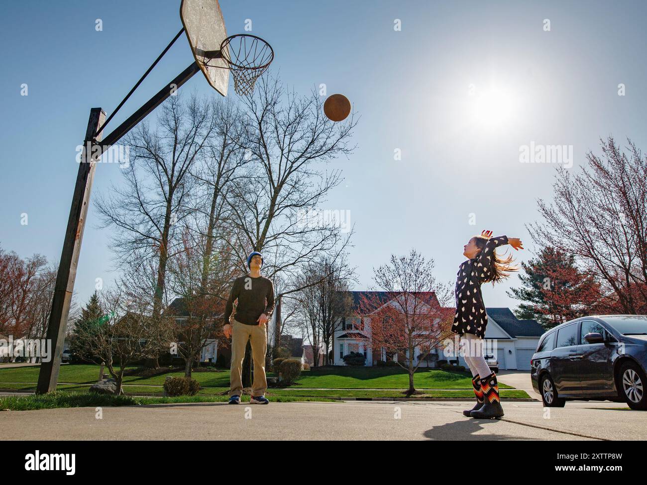 Enfant joyeux jette le basket-ball haut dans l'air pendant que le père regarde Banque D'Images