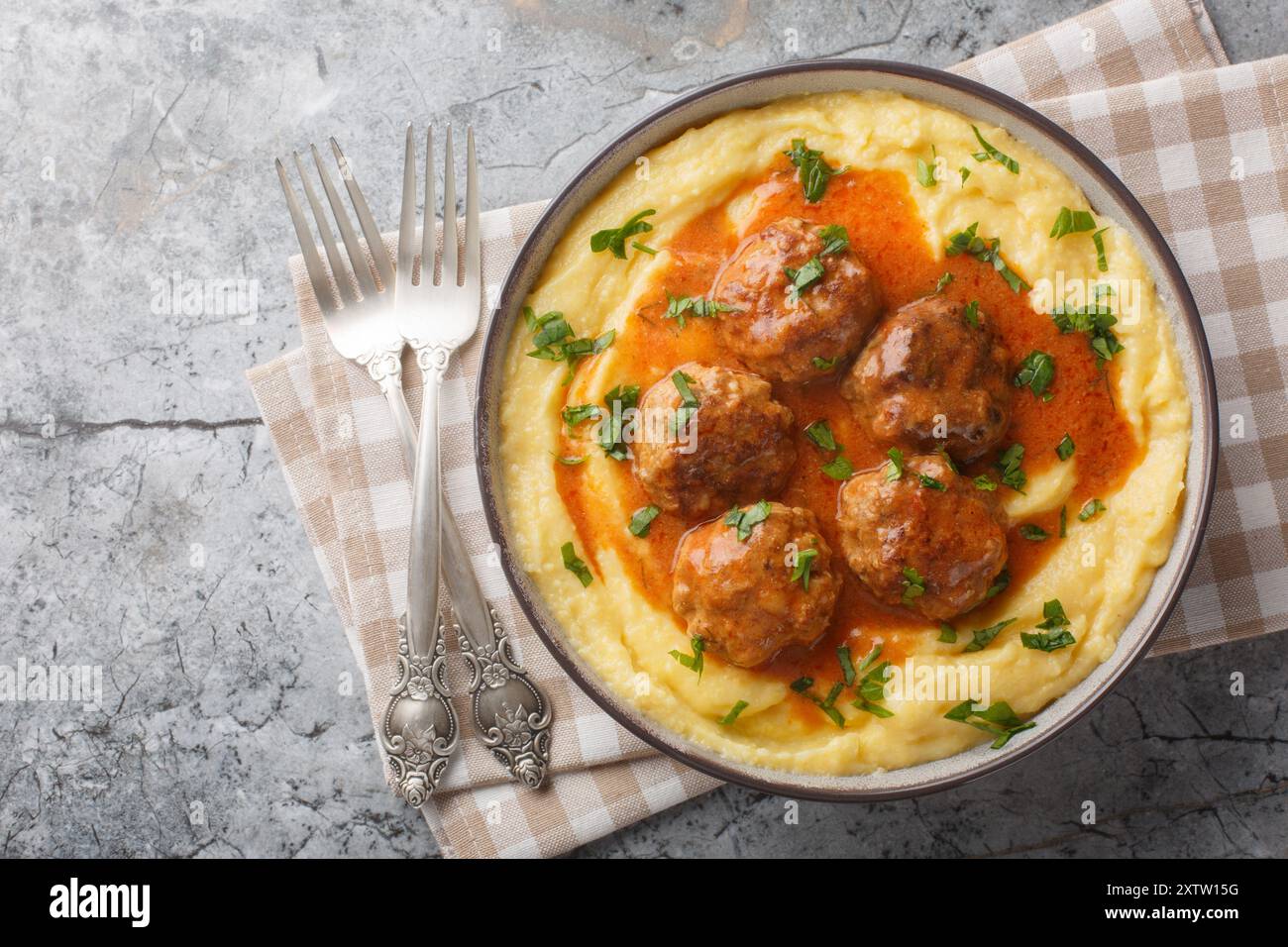Bouillie de maïs cuite avec boulettes de viande et sauce épicée gros plan dans un bol sur la table. Vue horizontale de dessus Banque D'Images