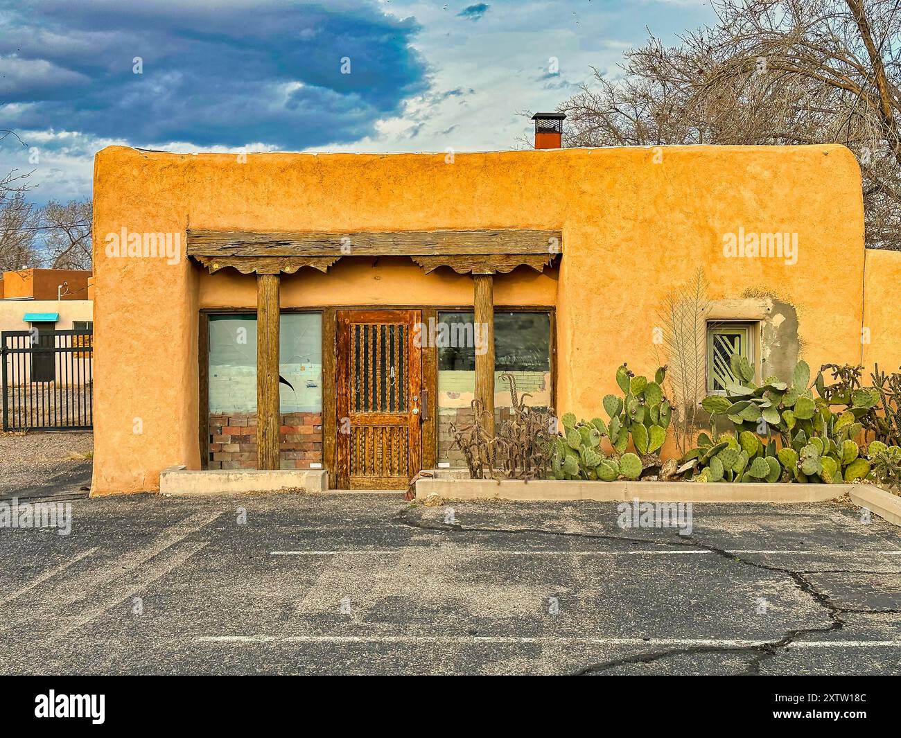 ALBUQUERQUE, NOUVEAU MEXIQUE, ÉTATS-UNIS - 8 MARS 2023. Vieille maison abandonnée en bois en argile jaune. Fenêtres et portes en bois. Cactus près de la maison Banque D'Images