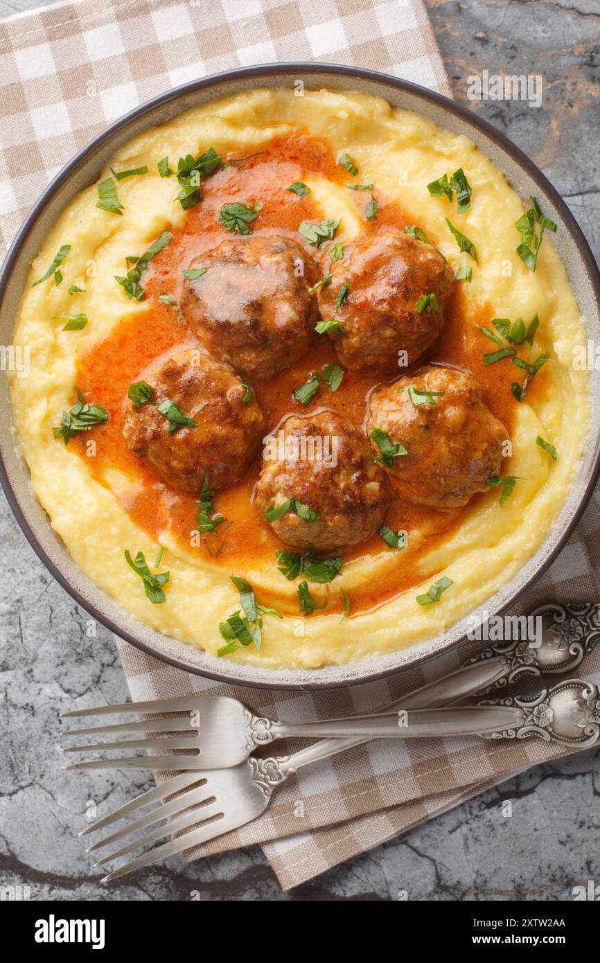 Polenta crémeuse et boulettes de viande avec sauce gros plan sur le bol sur la table. Vue de dessus verticale Banque D'Images