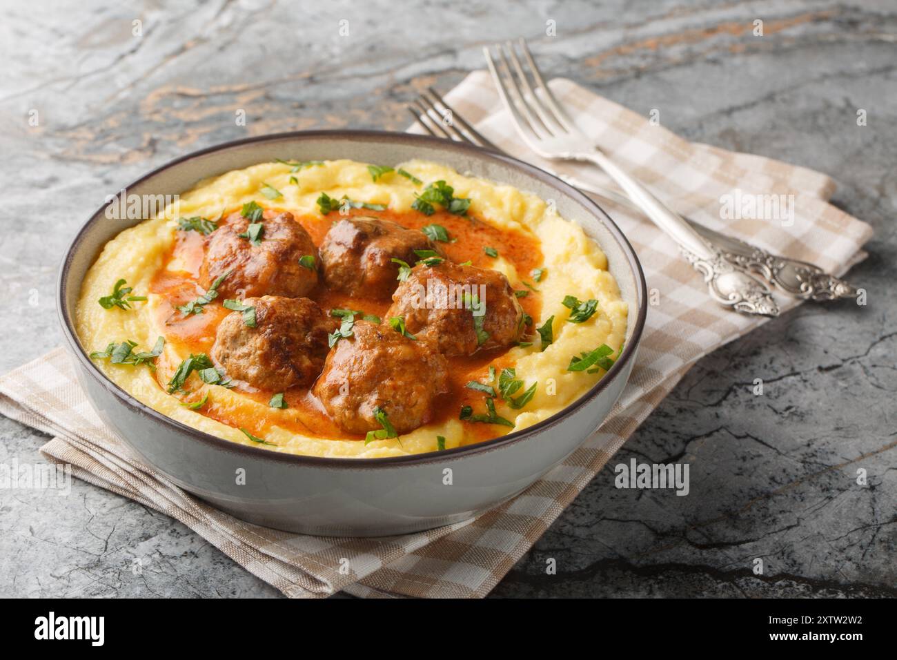 Bouillie de maïs cuite avec boulettes de viande et sauce épicée gros plan dans un bol sur la table. Horizontal Banque D'Images