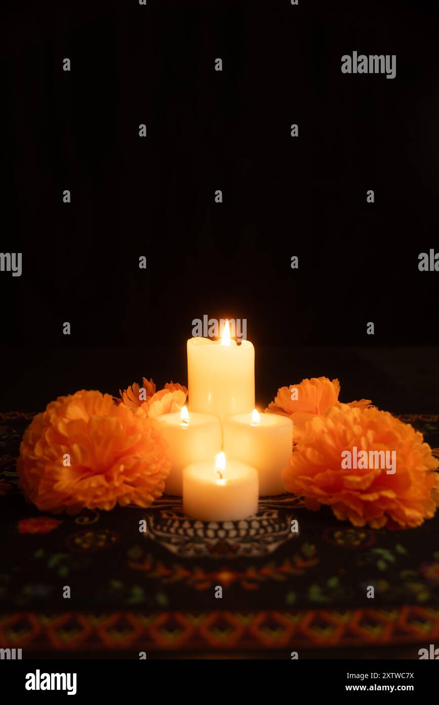 Une image verticale représentant trois bougies allumées au centre, entourées de fleurs de souci orange vives. Le fond noir et Day of the Dead Mo Banque D'Images