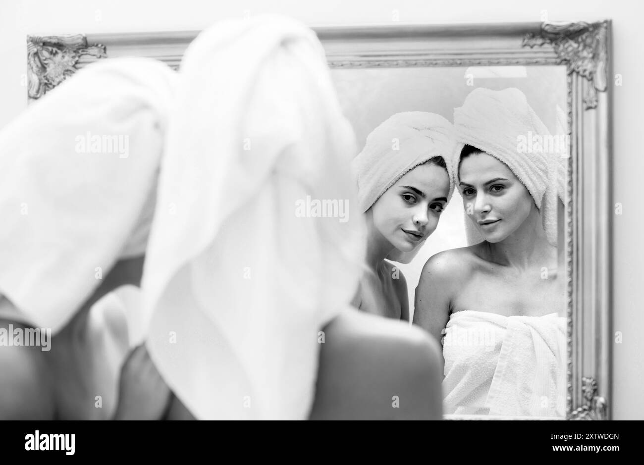 Gros plan belle femme regarder dans le miroir après la douche.Jeunes filles jolies amis enveloppés dans une serviette lissant la peau, routine quotidienne du matin Banque D'Images