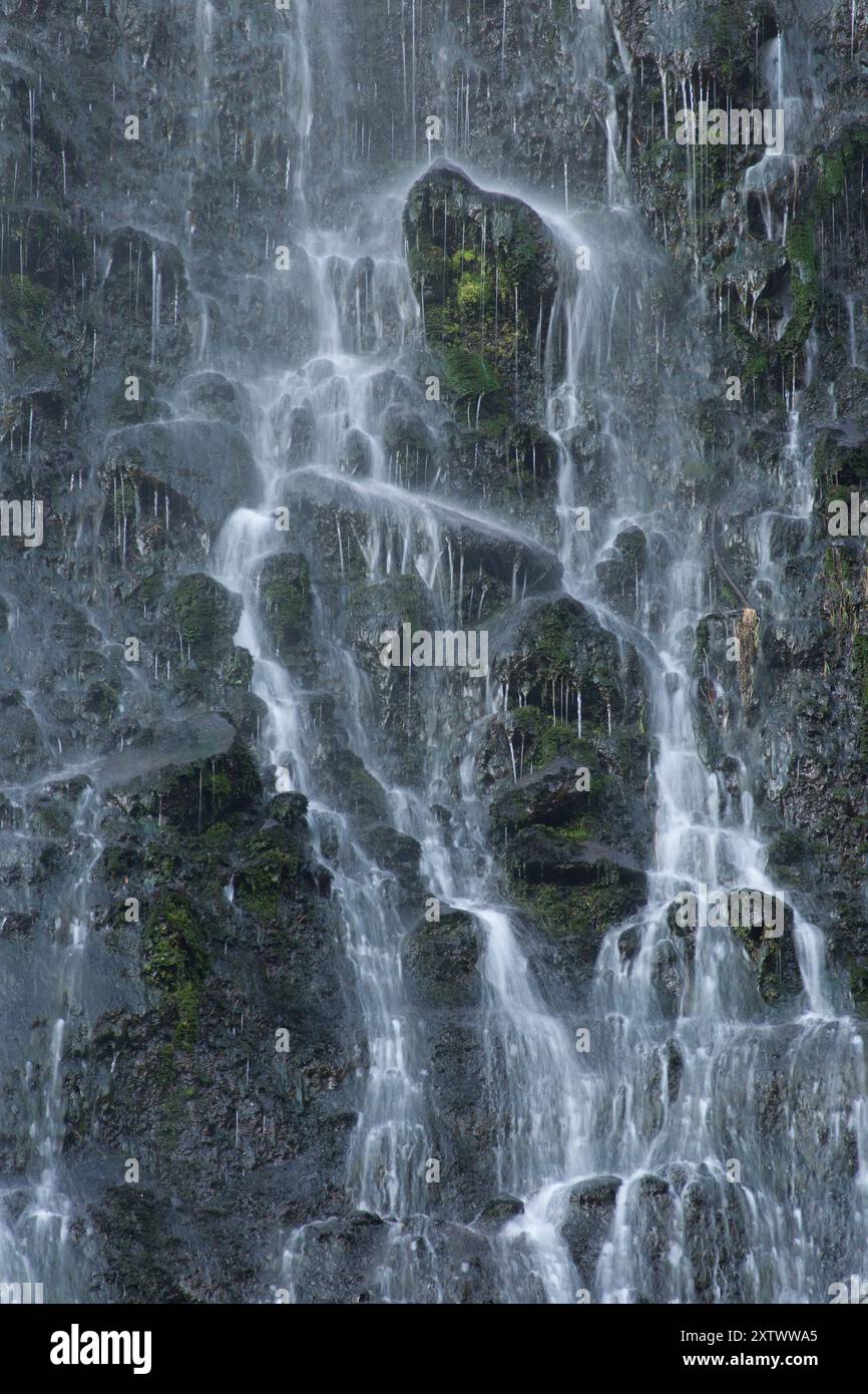 Gros plan d'une cascade majestueuse en cascade sur une surface rocheuse avec des gouttelettes d'eau créant une atmosphère brumeuse, Nouvelle-Zélande Banque D'Images