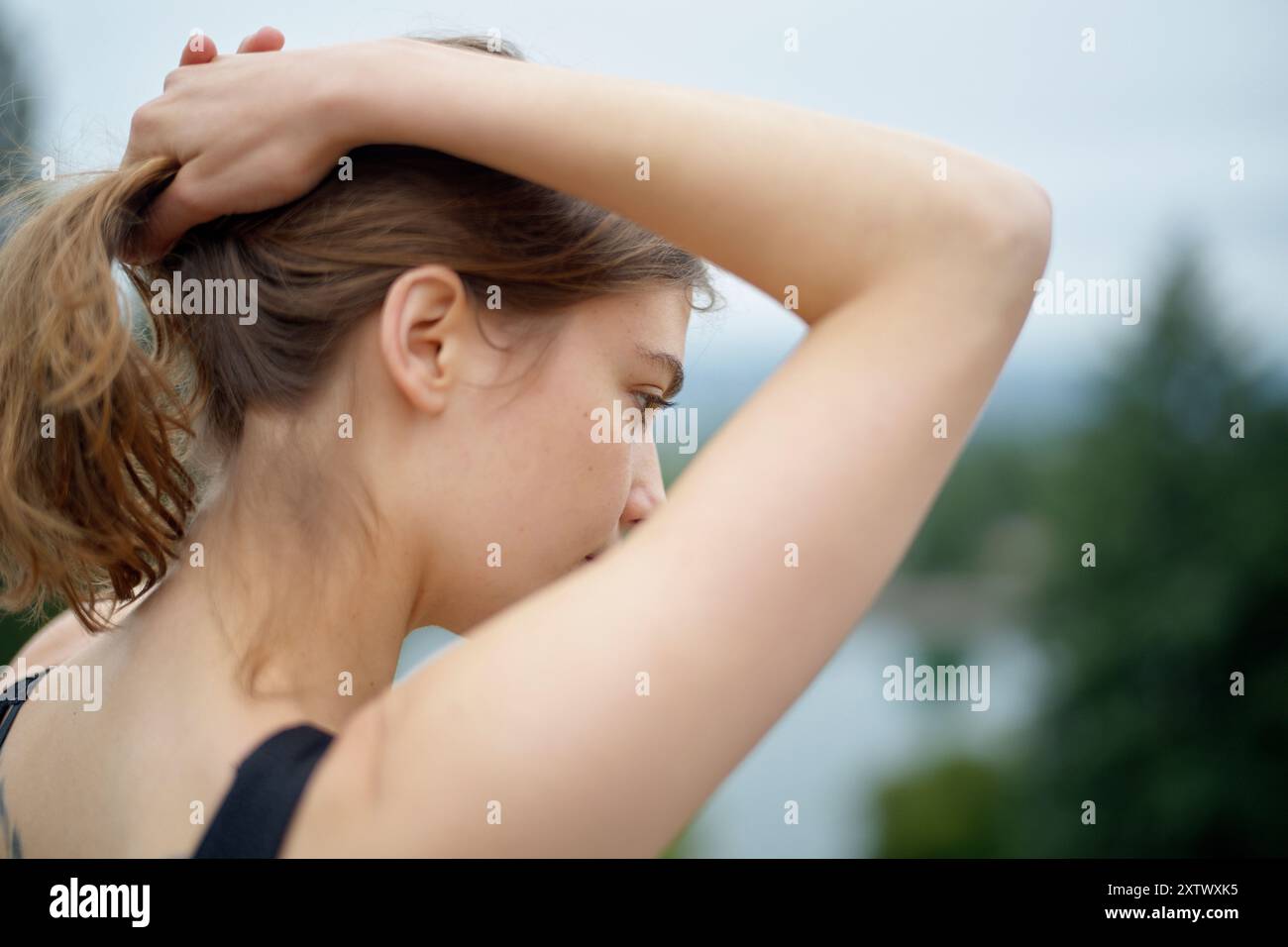 Femme avec ses cheveux attachés, vu de côté sur un fond naturel flou. Banque D'Images