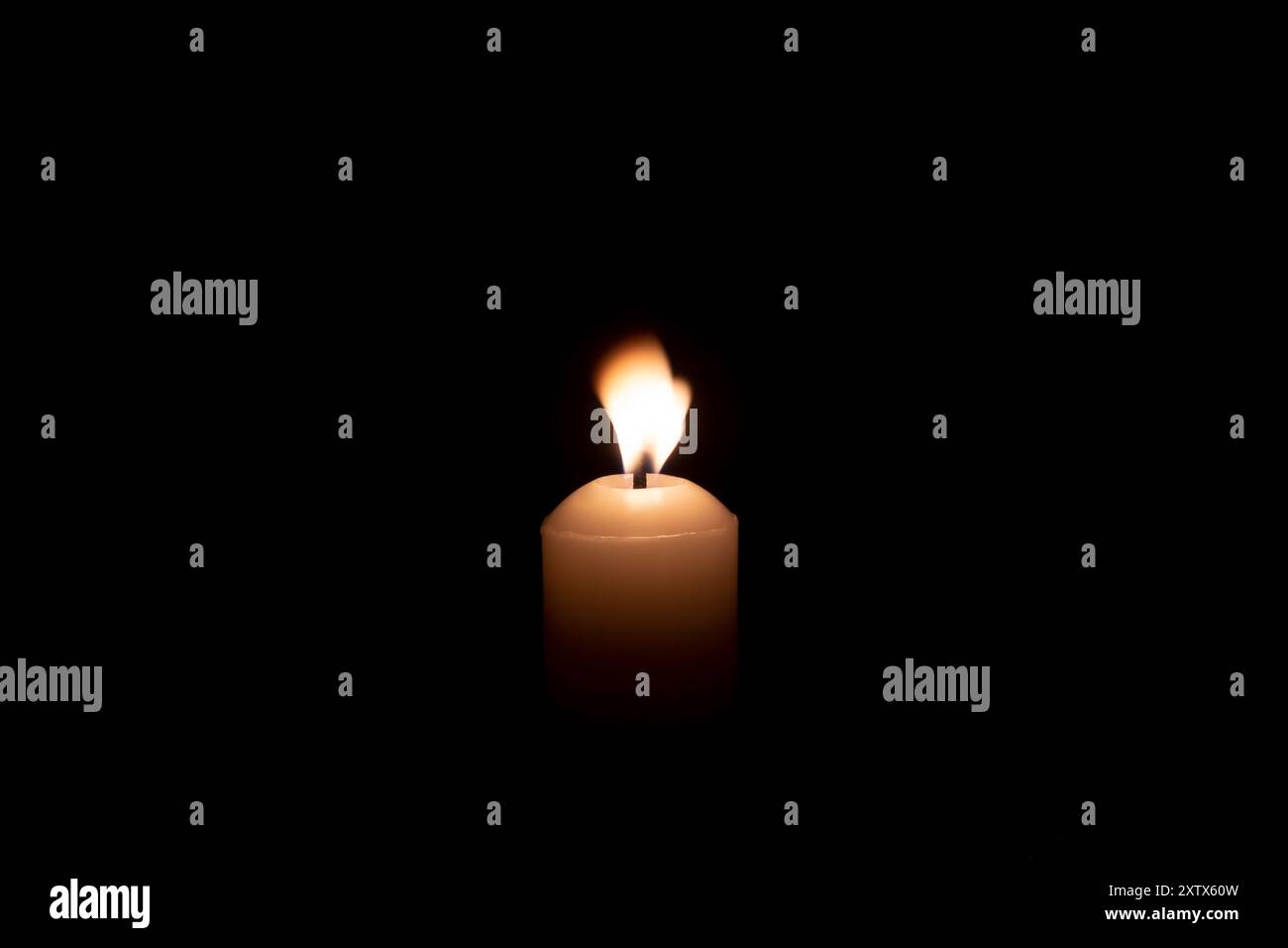 Une seule bougie luisant sur une grande bougie blanche contre le vent soufflant sur la table dans l'église pour Noël, funérailles ou service commémoratif avec espace de copie Banque D'Images