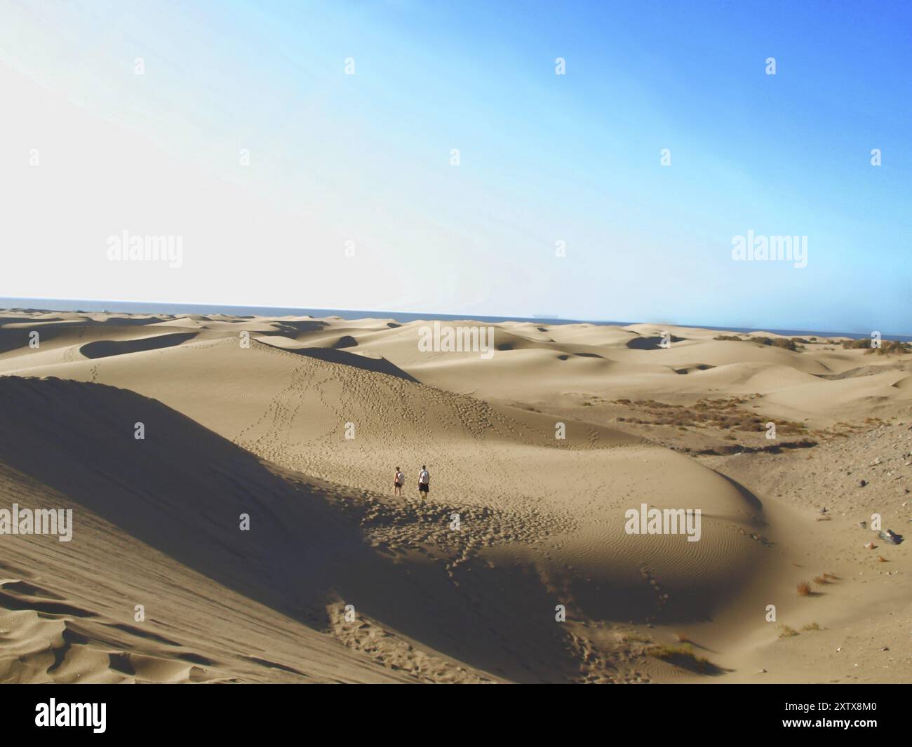 Des gens marchant dans un désert, ciel bleu Banque D'Images