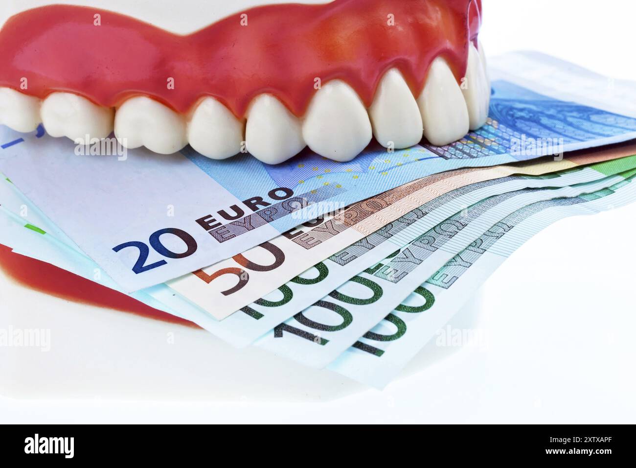 Un modèle dentaire chez le dentiste avec des billets en euros. Coûts pour la santé, studio Banque D'Images