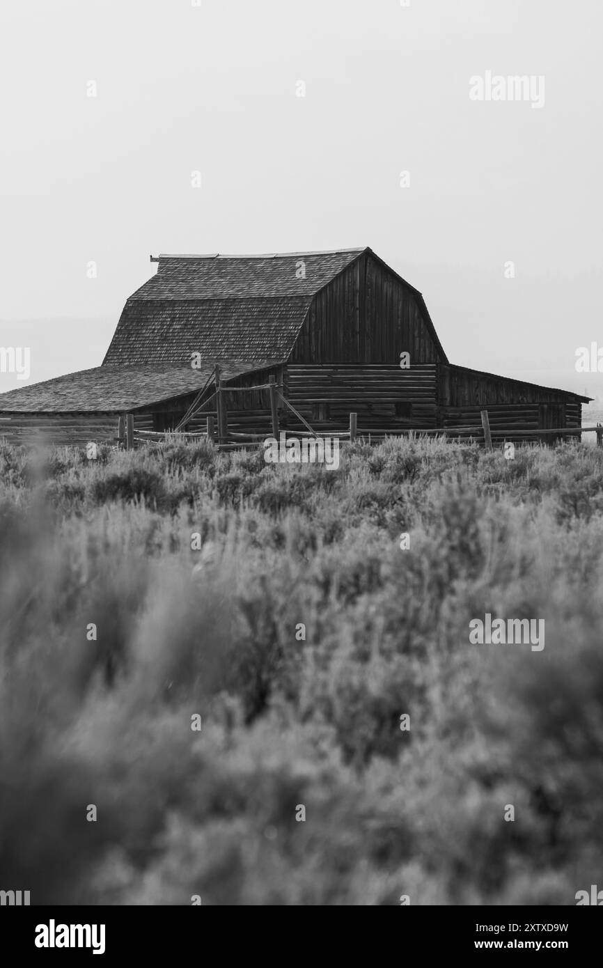 Une grange Mormon Row contre la chaîne de montagnes Grand Teton en noir et blanc Banque D'Images