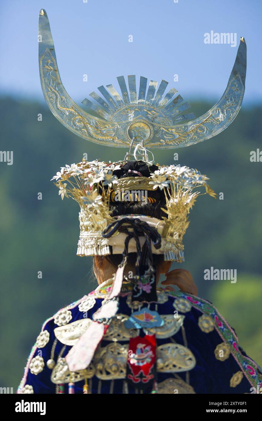 Xijiang, Chine, 15 septembre 2007 : vue arrière d'une femme Miao appartenant à une minorité ethnique dans des vêtements de festival traditionnels et coiffe argentée debout à Miao vill Banque D'Images
