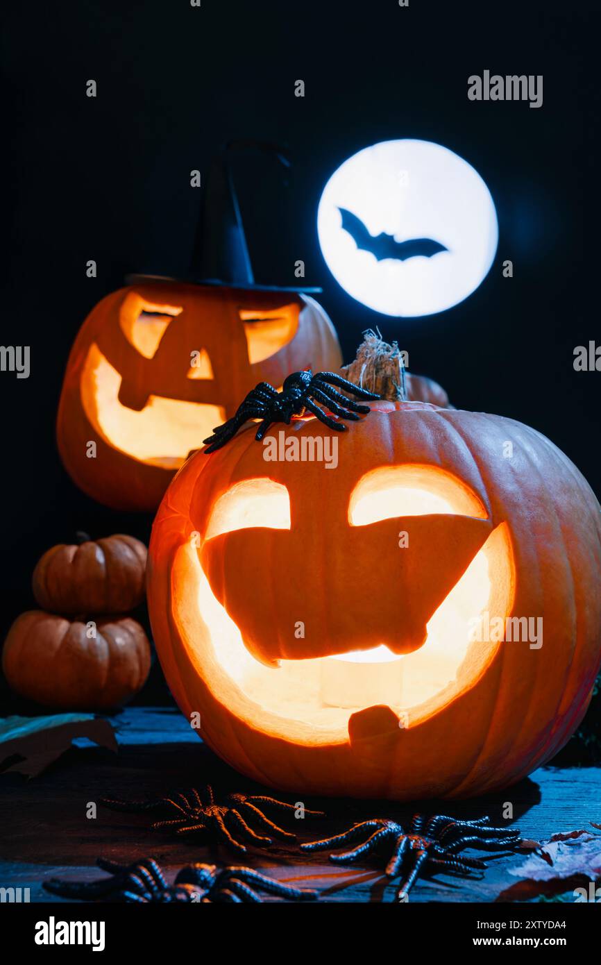 Deux Jack-O'-lanternes brillantes, des visages effrayants de citrouille, la pleine lune et la chauve-souris en arrière-plan, créant une scène d'Halloween effrayante Banque D'Images
