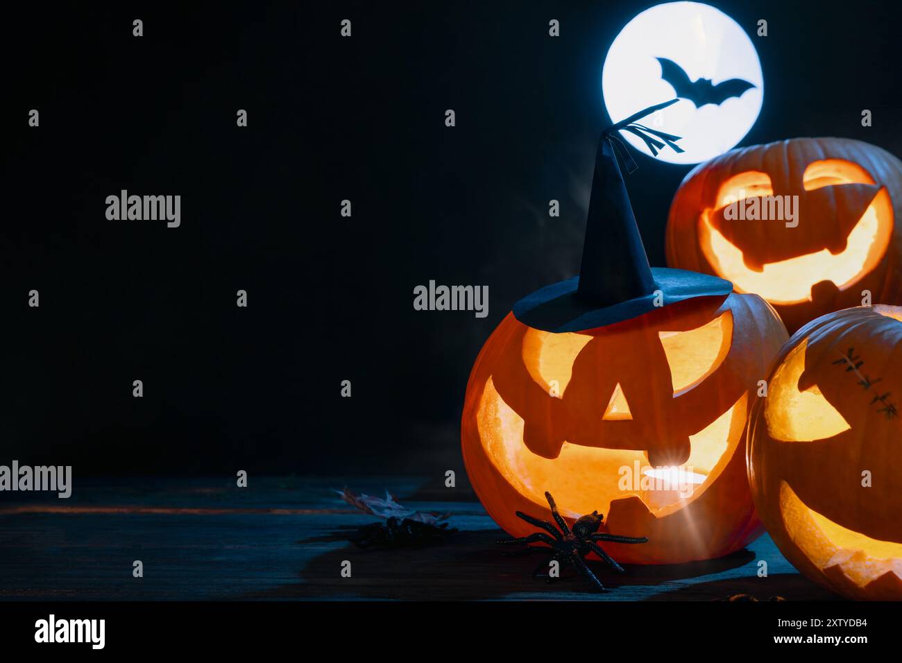 Empilé trois citrouilles sculptées avec illumination de bougie pour la décoration d'Halloween sur fond sombre avec pleine lune Banque D'Images