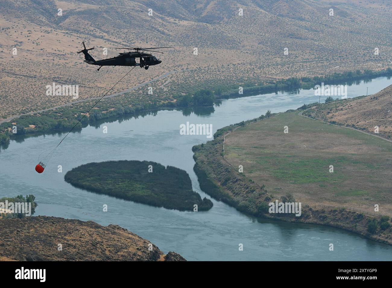 Snake River, Idaho, États-Unis. 29 juillet 2024. Un équipage d'hélicoptère UH-60 Black Hawk de la Garde nationale de l'Idaho mène une formation en seau d'eau au-dessus de la rivière Snake dans l'Idaho, le 29 juillet 2024. Les équipes de gardes s'entraînent pour rester prêtes à réagir aux feux de forêt. (Crédit image : © U.S. Army/ZUMA Press Wire) USAGE ÉDITORIAL SEULEMENT! Non destiné à UN USAGE commercial ! Banque D'Images