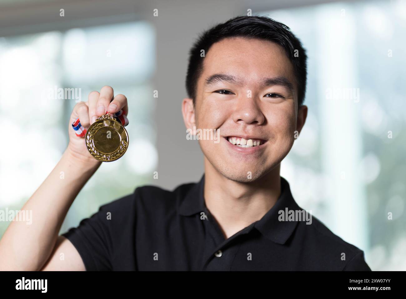 Un jeune étudiant adolescent tient une médaille d'or après avoir remporté la première place dans un portrait en gros plan d'une compétition sportive Banque D'Images