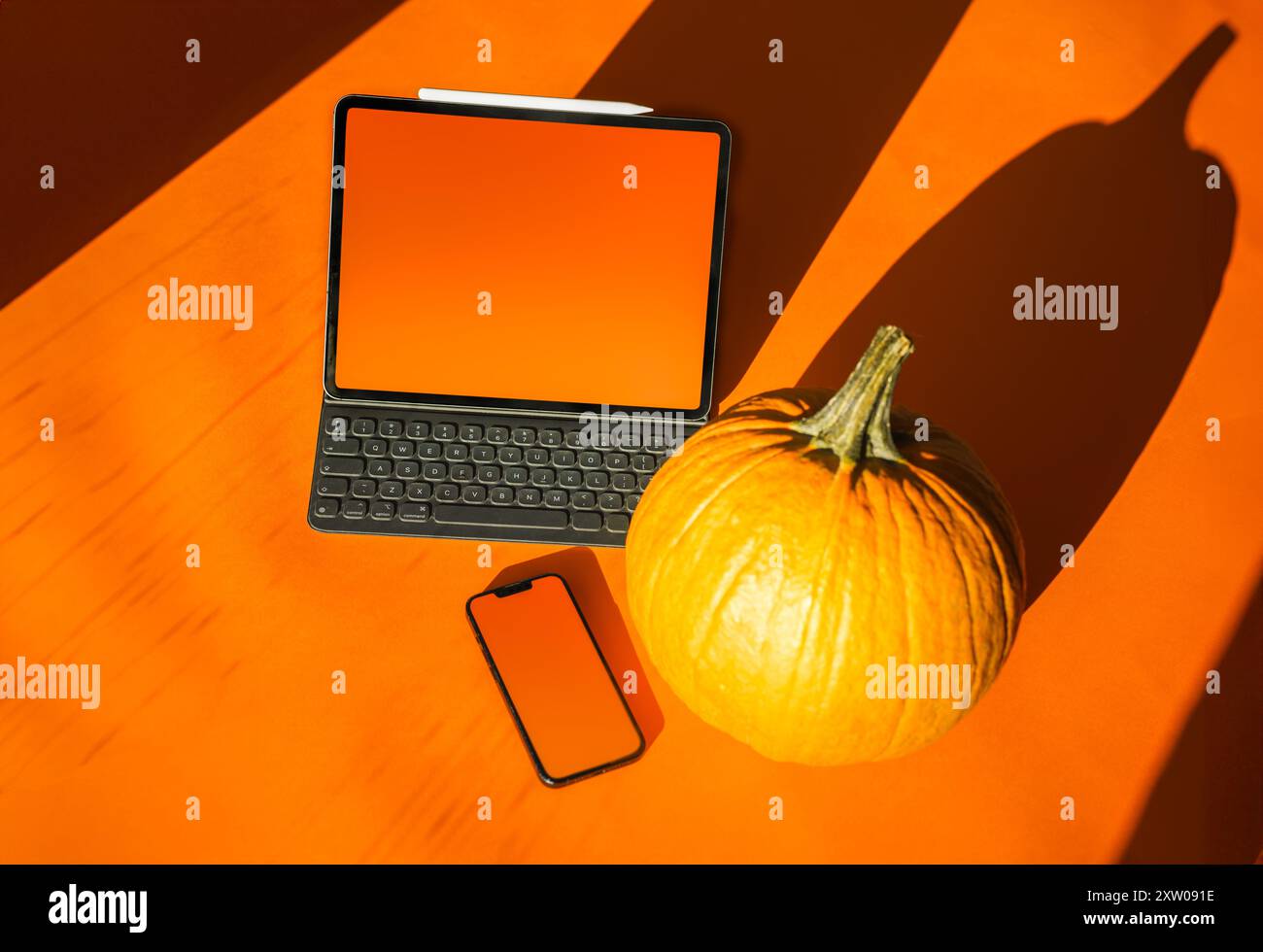 Smartphone et ordinateur portable. Couleurs d'automne. Fond orange. Citrouille d'automne. Maquette d'écran vide. Banque D'Images