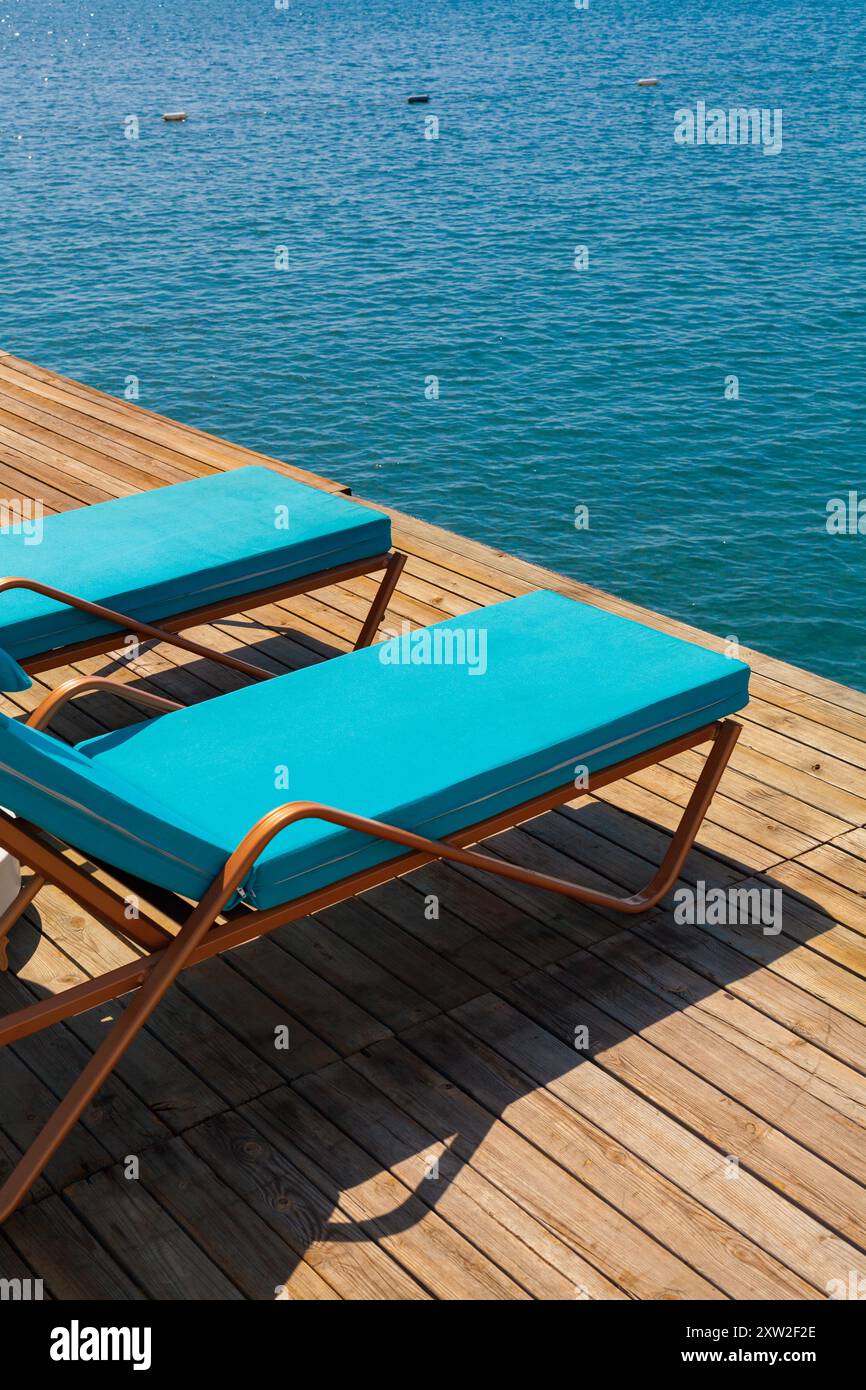 Groupe de chaises longues de luxe sur une jetée en bois en attente pour les touristes dans une chaude journée d'été. Voyage, tourisme, loisirs et concept de vacances. Banque D'Images