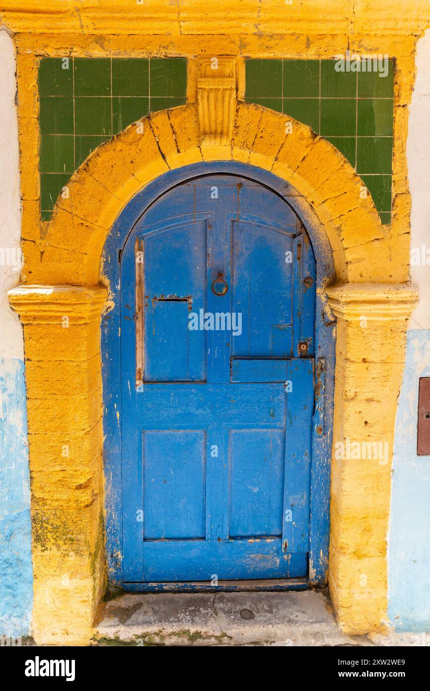 Dans une rue étroite de la médina d'Essaouira, cette porte en bois bleu et son cadre en pierre jaune Banque D'Images