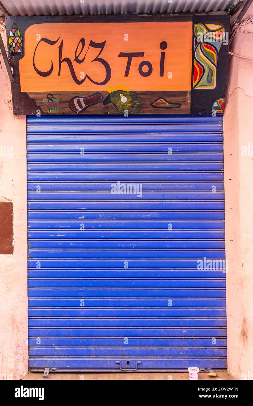 'Chez toi' (chez vous) : panneau apposé au-dessus d'une porte protégée par un volet bleu fermé Banque D'Images