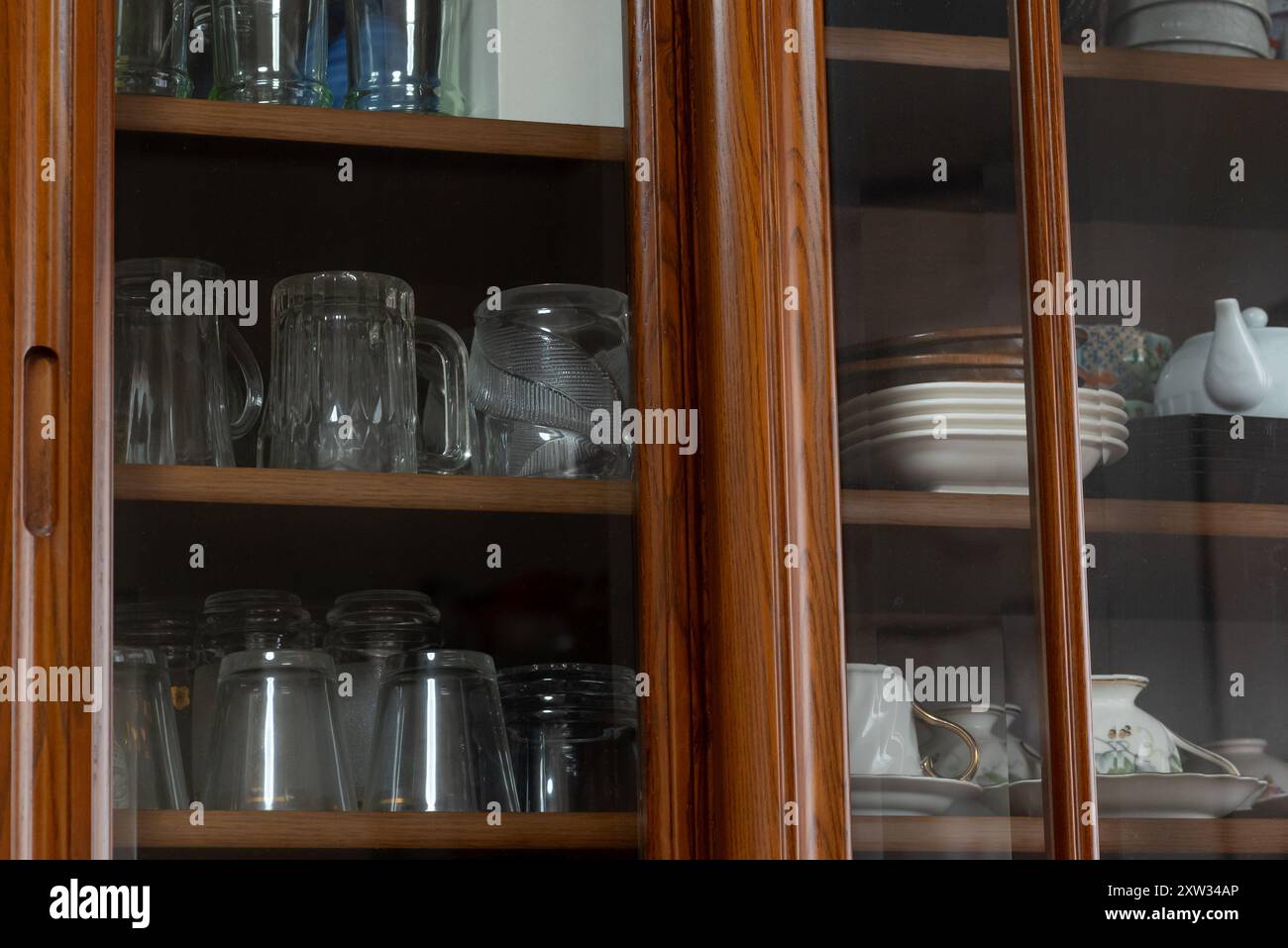 La vaisselle et les verres sont stockés dans une armoire en bois à porte vitrée Banque D'Images