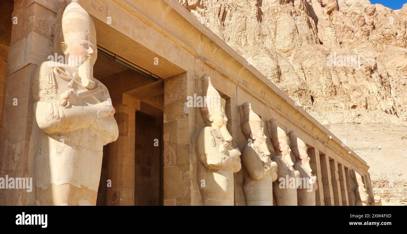 Des statues massives de la Grande femme Pharoah Hatshepsout avec l'escroc et le fléau en tant que souverain de l'Égypte sculpté dans le grès dominent les colonnes extérieures du Temple mortuaire près de Louxor, en Égypte Banque D'Images