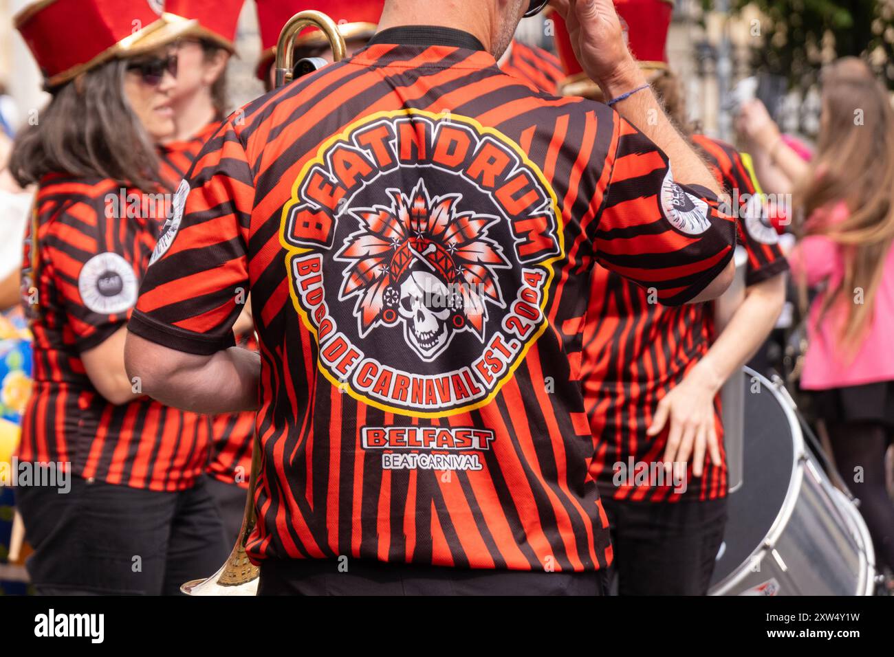 Belfast Mela Carnival Parade, groupe de samba Beat N Drum avec chemises colorées rouges et noires et tambours argentés. Belfast, Royaume-Uni - 17 août 2024. Banque D'Images