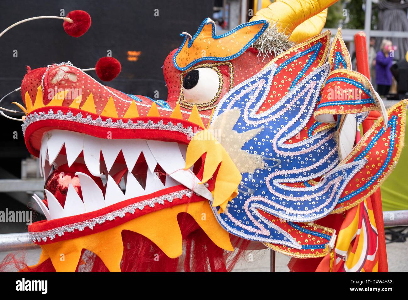 Parade annuelle du carnaval de Belfast Mela - gros plan sur la tête du dragon dansant chinois dans des couleurs rouges et oranges saisissantes. Belfast, Royaume-Uni - 17 août 2024. Banque D'Images