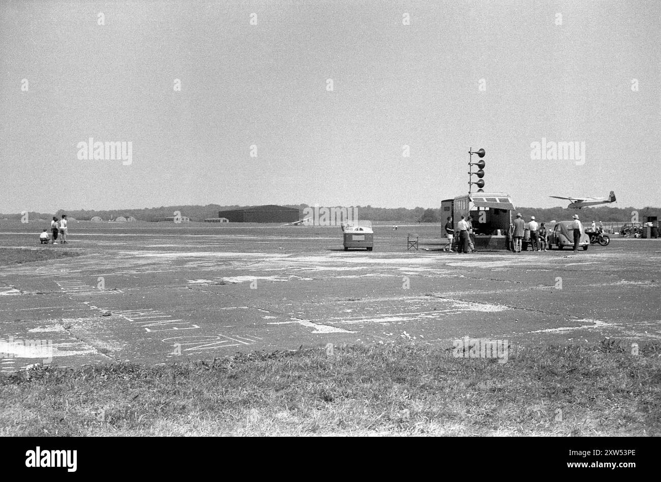 Angleterre. Circa.1957 - Une réunion de club de planeurs sur un aérodrome britannique. Un groupe de membres du club entoure une caravane de sonorisation, regardant un planeur entrer à terre. Banque D'Images