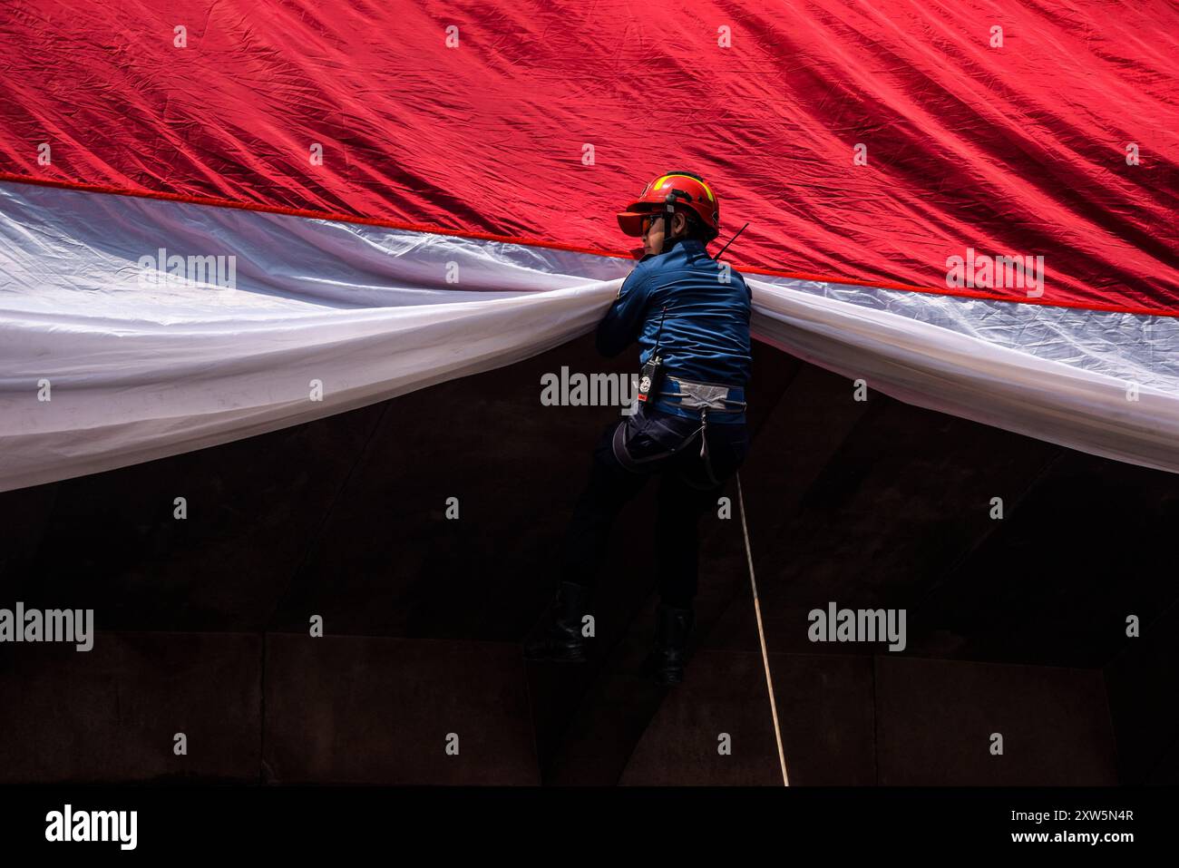 Bandung, Java occidental, Indonésie. 17 août 2024. Un pompier descend d'un pont pour hisser un drapeau rouge et blanc géant lors d'un salut de trois minutes commémorant le 79e jour de l'indépendance de la République d'Indonésie à Bandung, Java occidental. (Crédit image : © Dimas Rachmatsyah/Pacific Press via ZUMA Press Wire) USAGE ÉDITORIAL SEULEMENT! Non destiné à UN USAGE commercial ! Banque D'Images