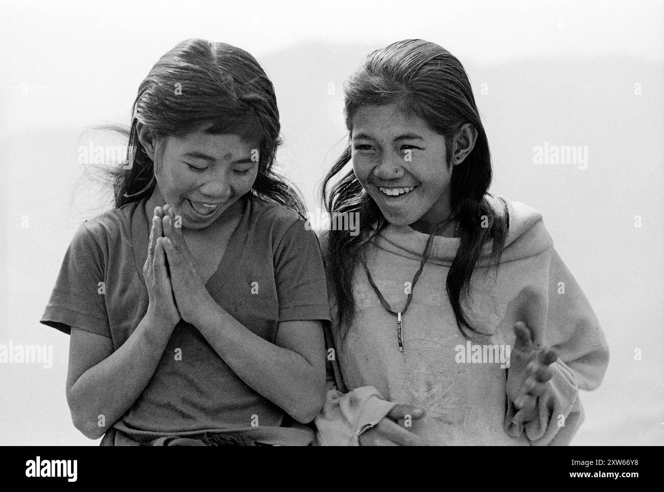 Deux sœurs riantes donnent le salut Namaste dans les collines moyennes du Népal sur le trek du sanctuaire Annapurna - Népal 1988 Banque D'Images