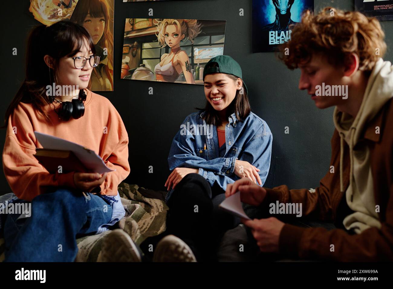 Groupe de jeunes adultes engagés dans la conversation sur diverses œuvres d'art exposées sur les murs. Ambiance décontractée avec dialogue favorisant la créativité et la collaboration Banque D'Images