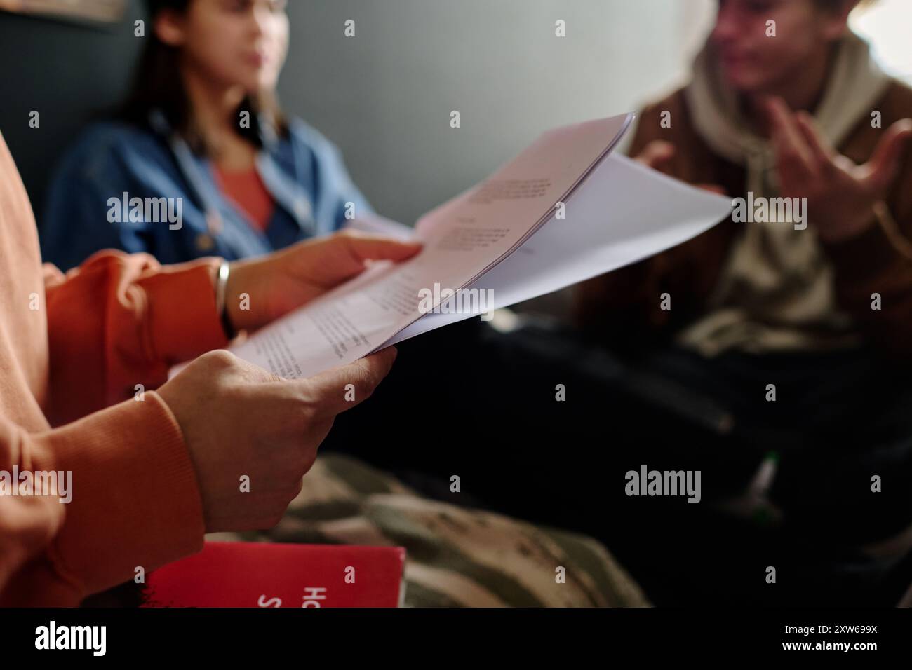 Groupe de personnes examinant un document important dans un cadre confortable et s'engageant dans une discussion animée. La paperasserie et les tenues décontractées suggèrent une atmosphère détendue mais concentrée Banque D'Images