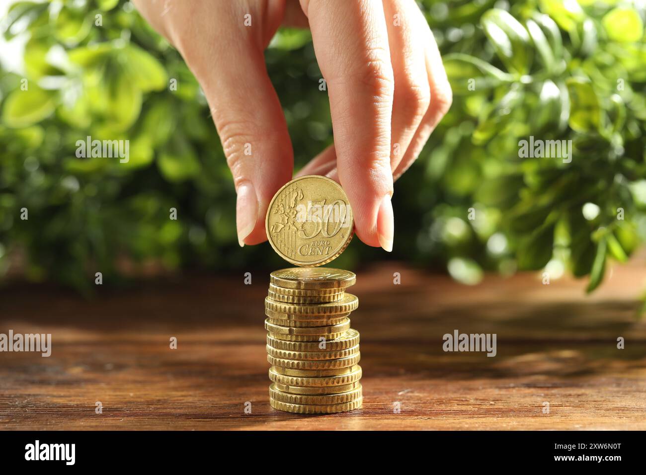 Femme empilant des pièces de monnaie sur une table en bois, gros plan Banque D'Images