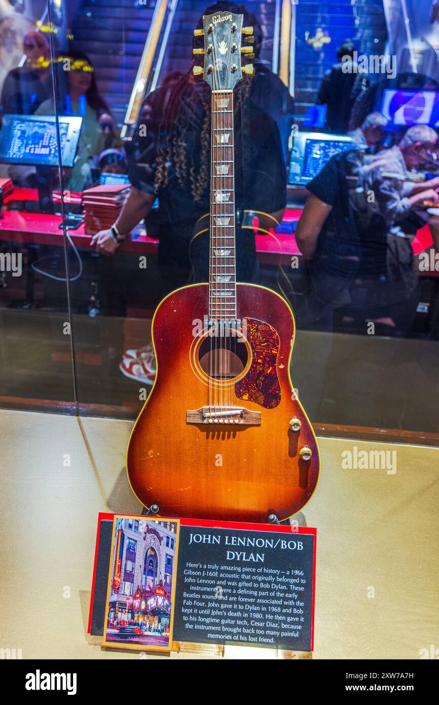 Guitare exposée au Hard Rock Cafe de Manhattan, avec John Lennon et Bob Dylan, avec plaque détaillant l'histoire de Gibson G-160E Acoustic 1966. Banque D'Images