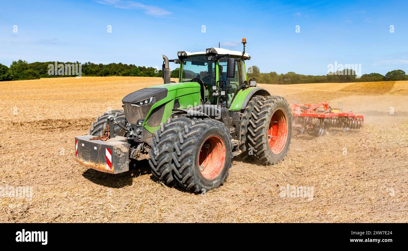 Tracteur avec pneus jumelés et cultivateur au travail dans le champ après la récolte des céréales - N° 2020 Banque D'Images