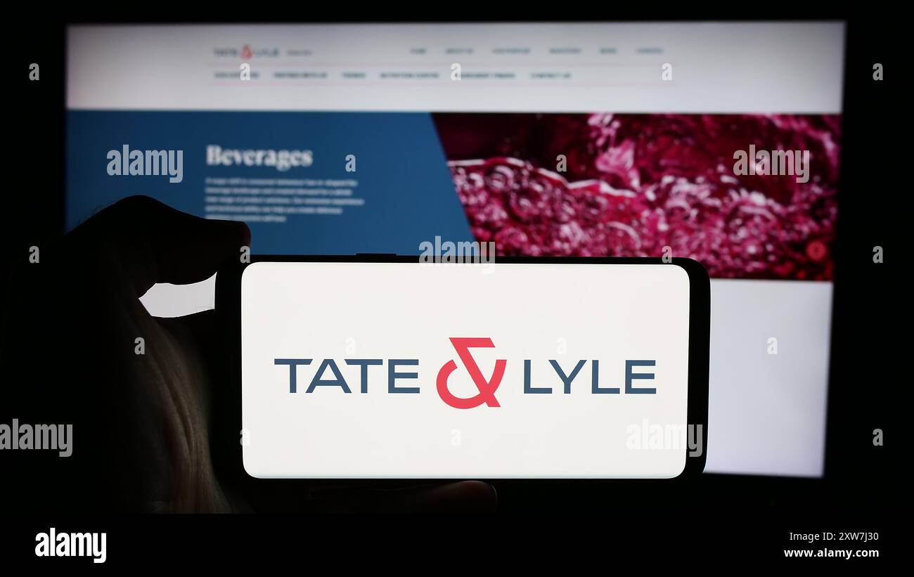 Personne tenant un téléphone portable avec le logo de la société britannique de transformation des aliments Tate et Lyle plc devant la page Web de l'entreprise. Concentrez-vous sur l'affichage du téléphone. Banque D'Images