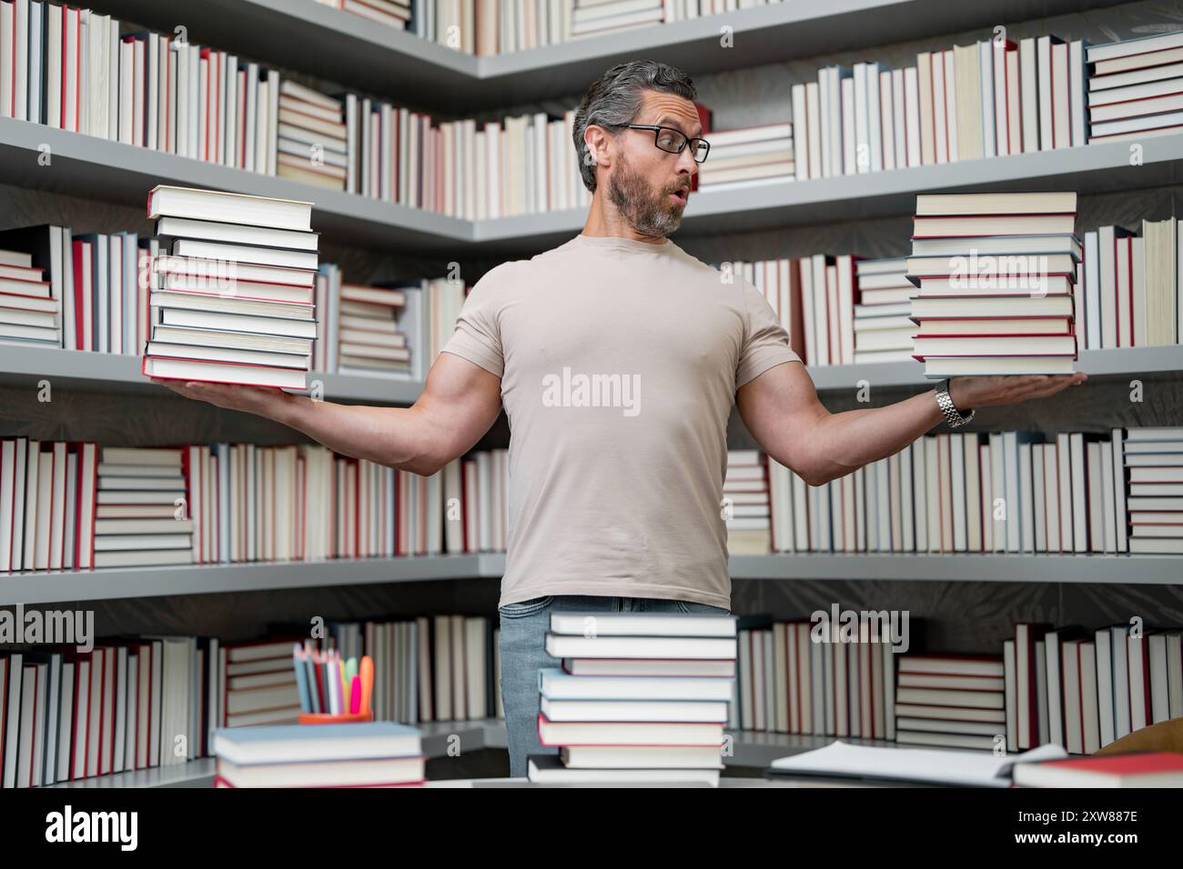 Drôle d'enseignant de tenir beaucoup de livres. Professeur fou avec des livres. Enseignant enthousiaste dans la bibliothèque de livres de l'école. Examen universitaire. Étudier enseigner à l'université. Éducateur Banque D'Images